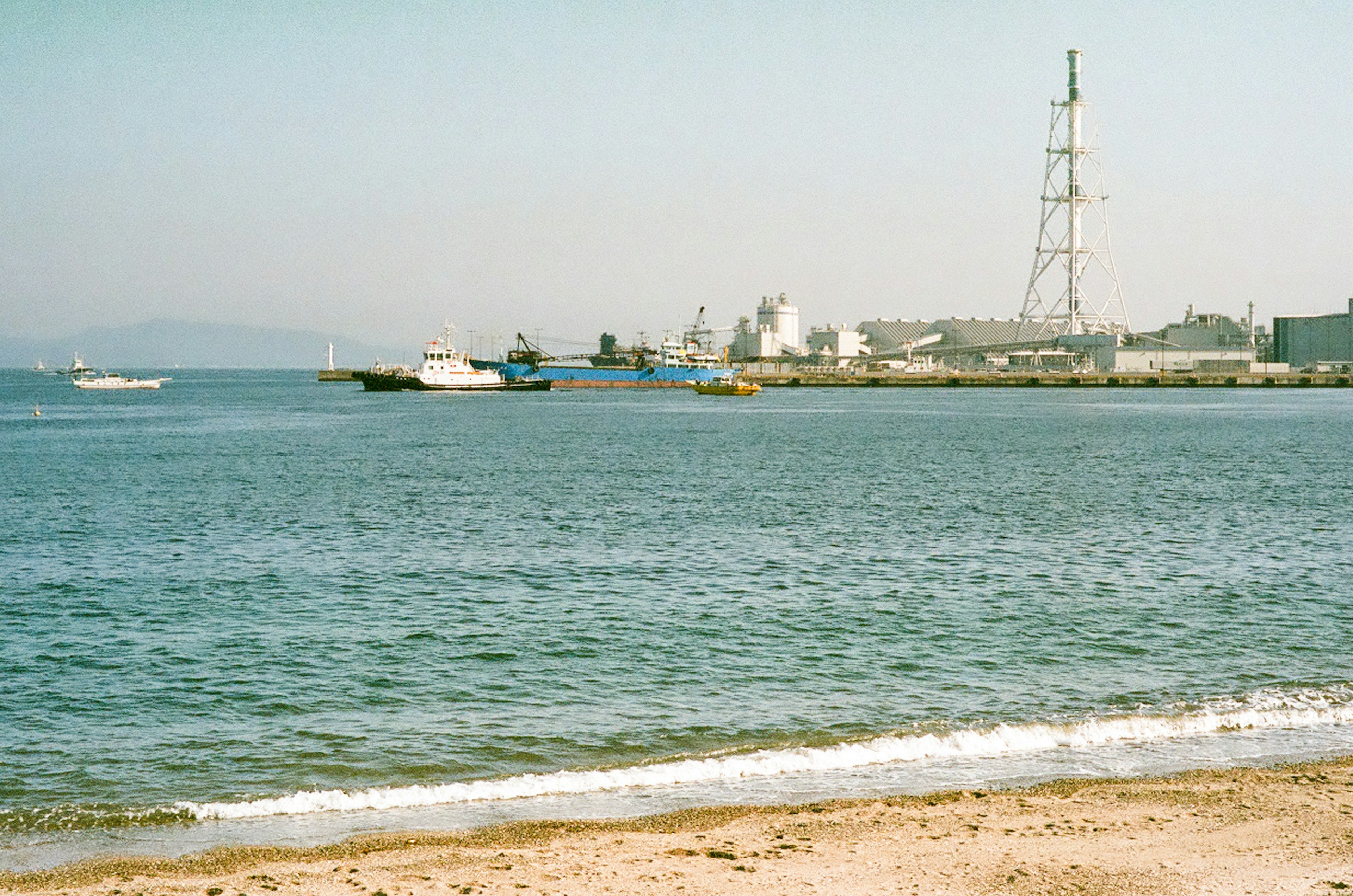 Küstenansicht mit Wasser Booten und Industriegebiet