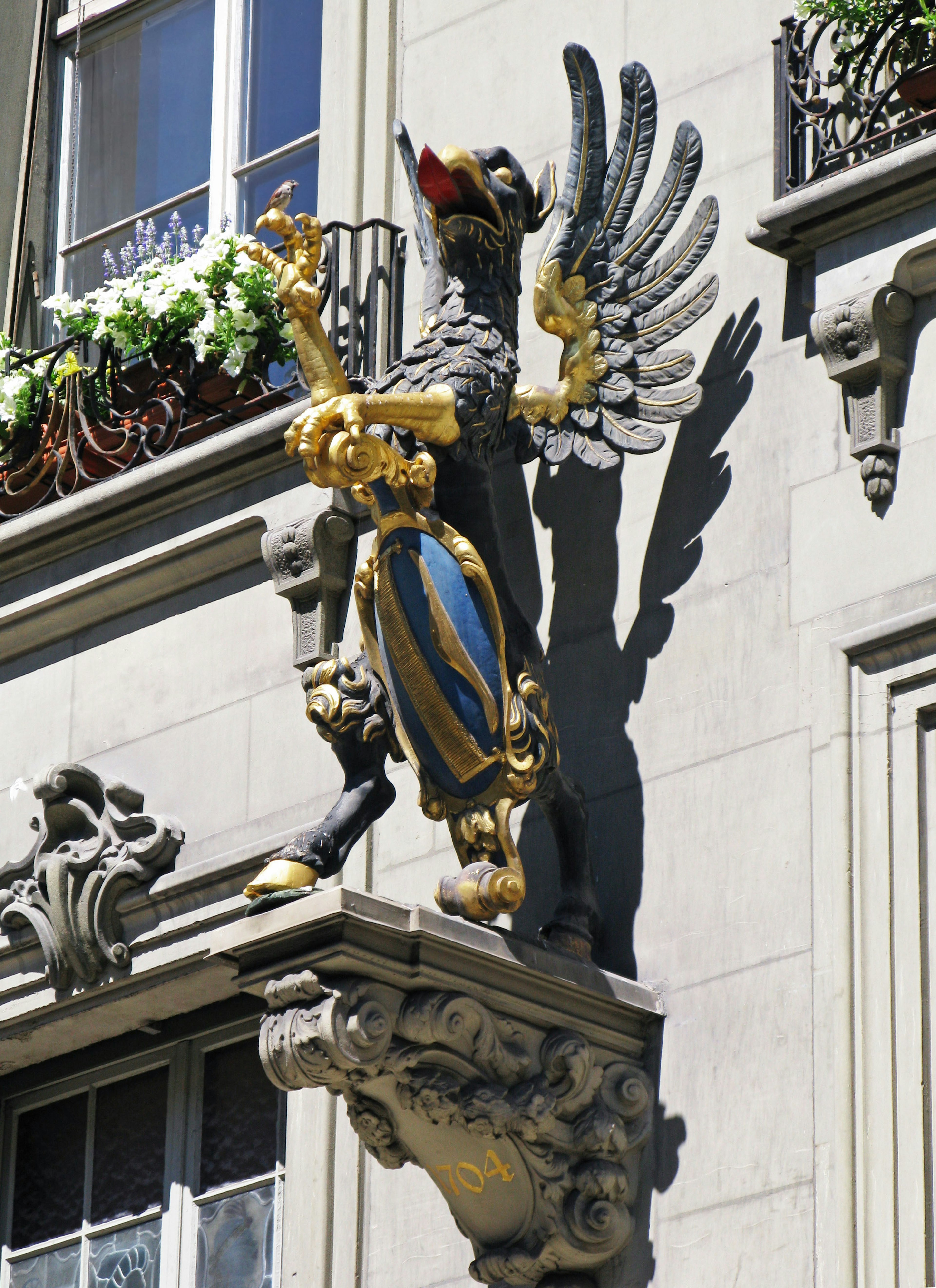 Sculpture de griffon doré avec des ailes montée sur un mur de bâtiment