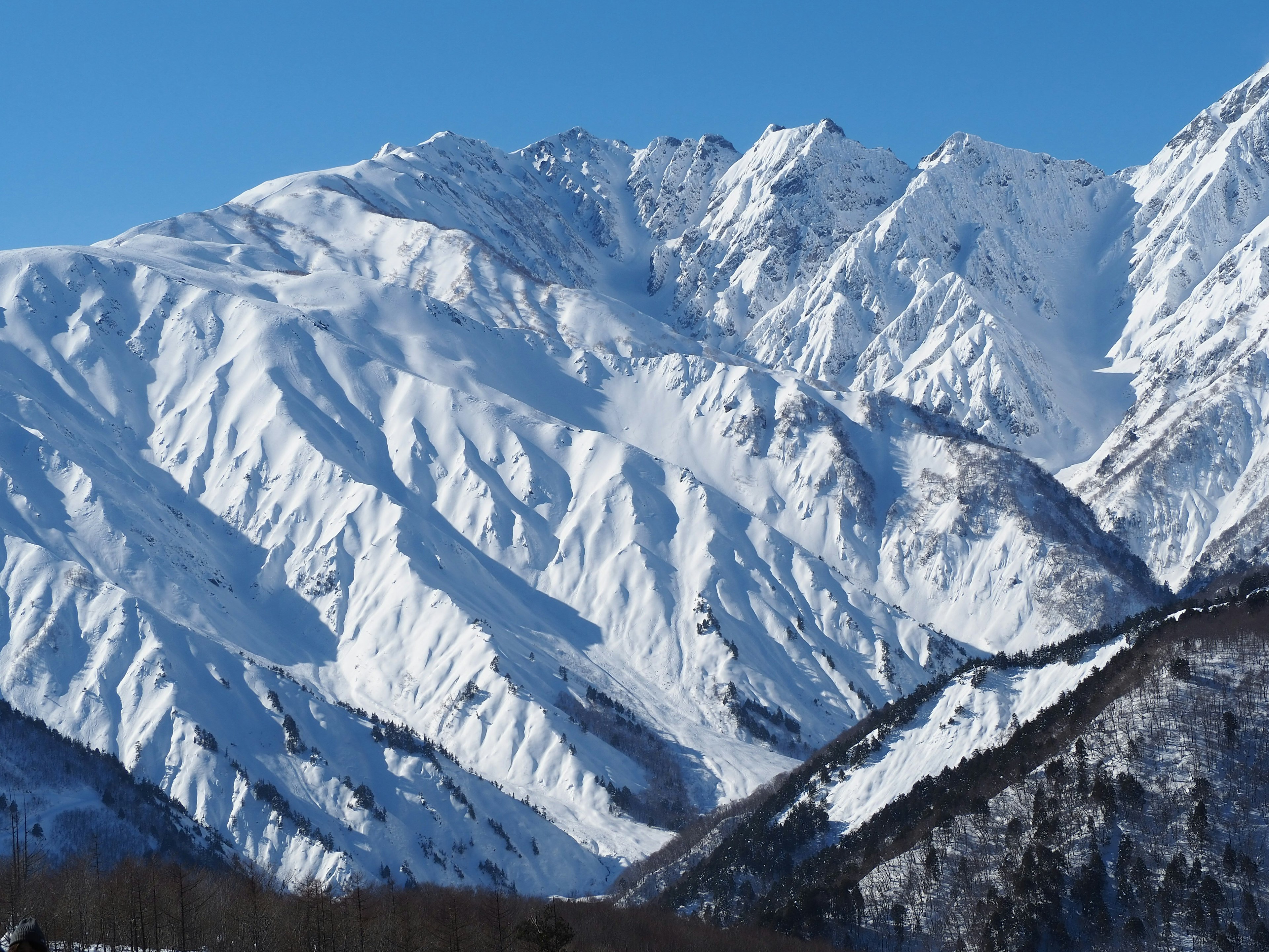 Paesaggio montano coperto di neve con cielo azzurro chiaro e contrasto di neve bianca