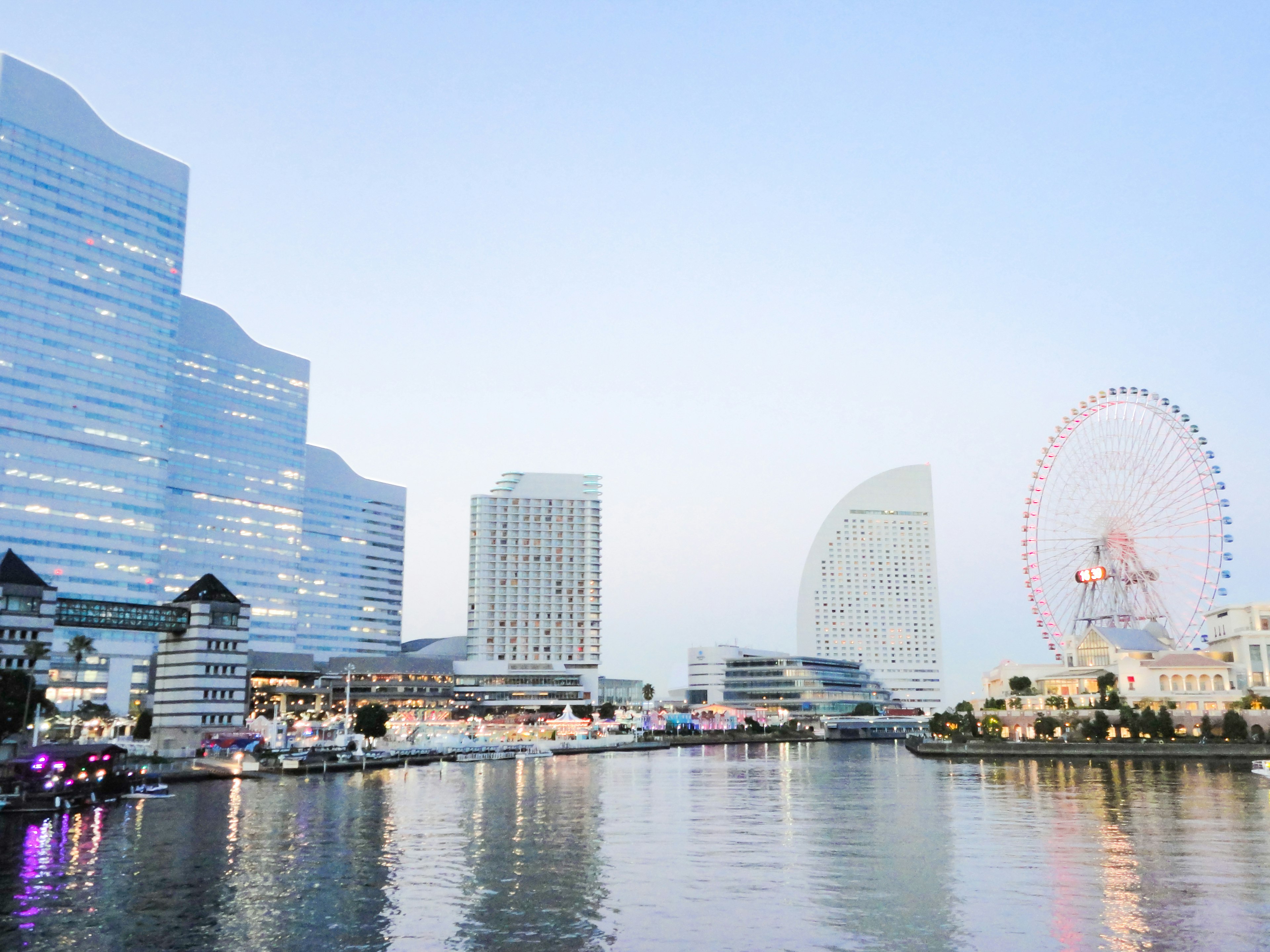 Modern buildings along a waterfront with a Ferris wheel