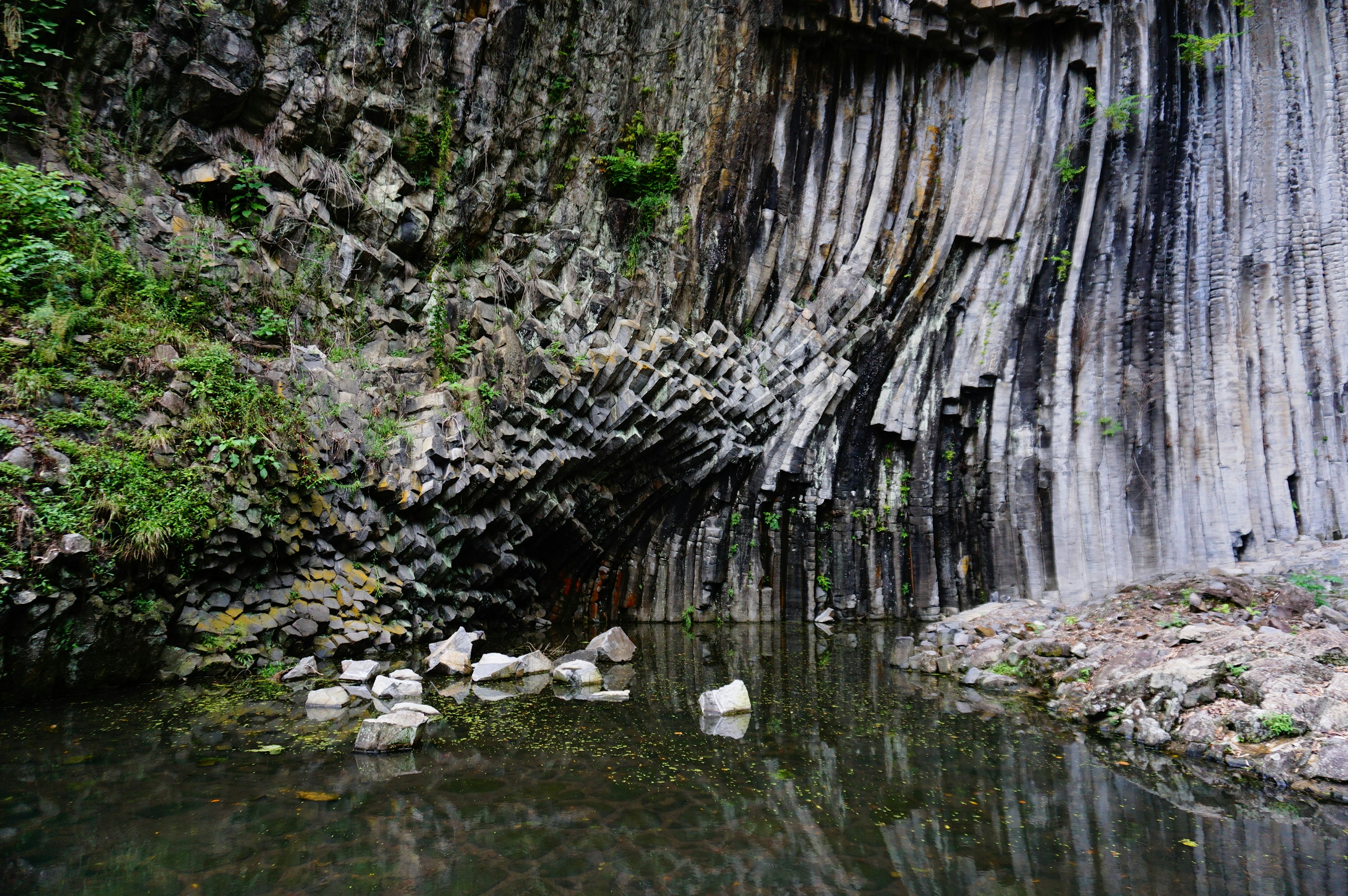 Beautiful columnar jointing cliff with calm water surface