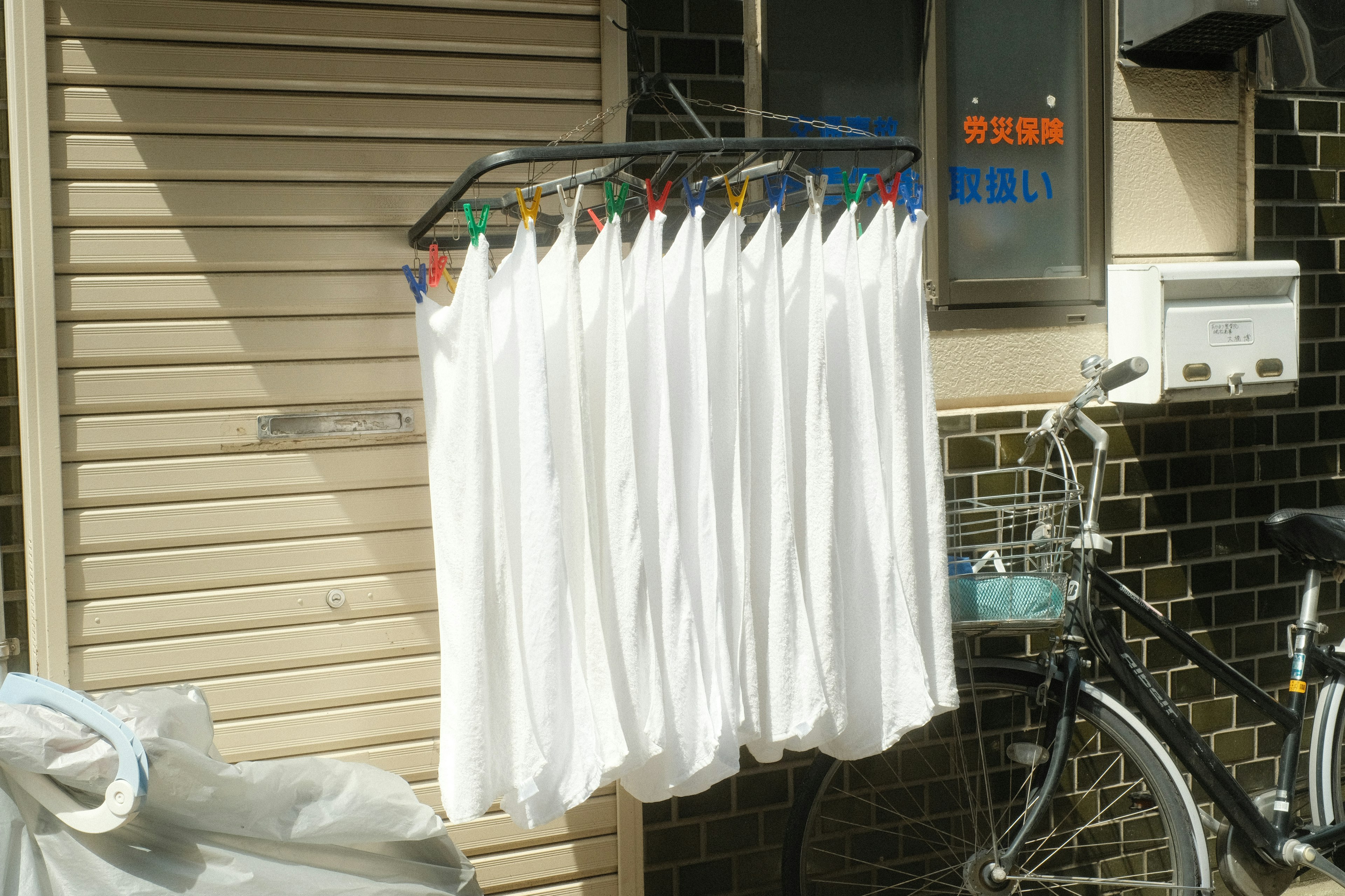 Clothes drying rack with white fabric hanging and bicycle nearby