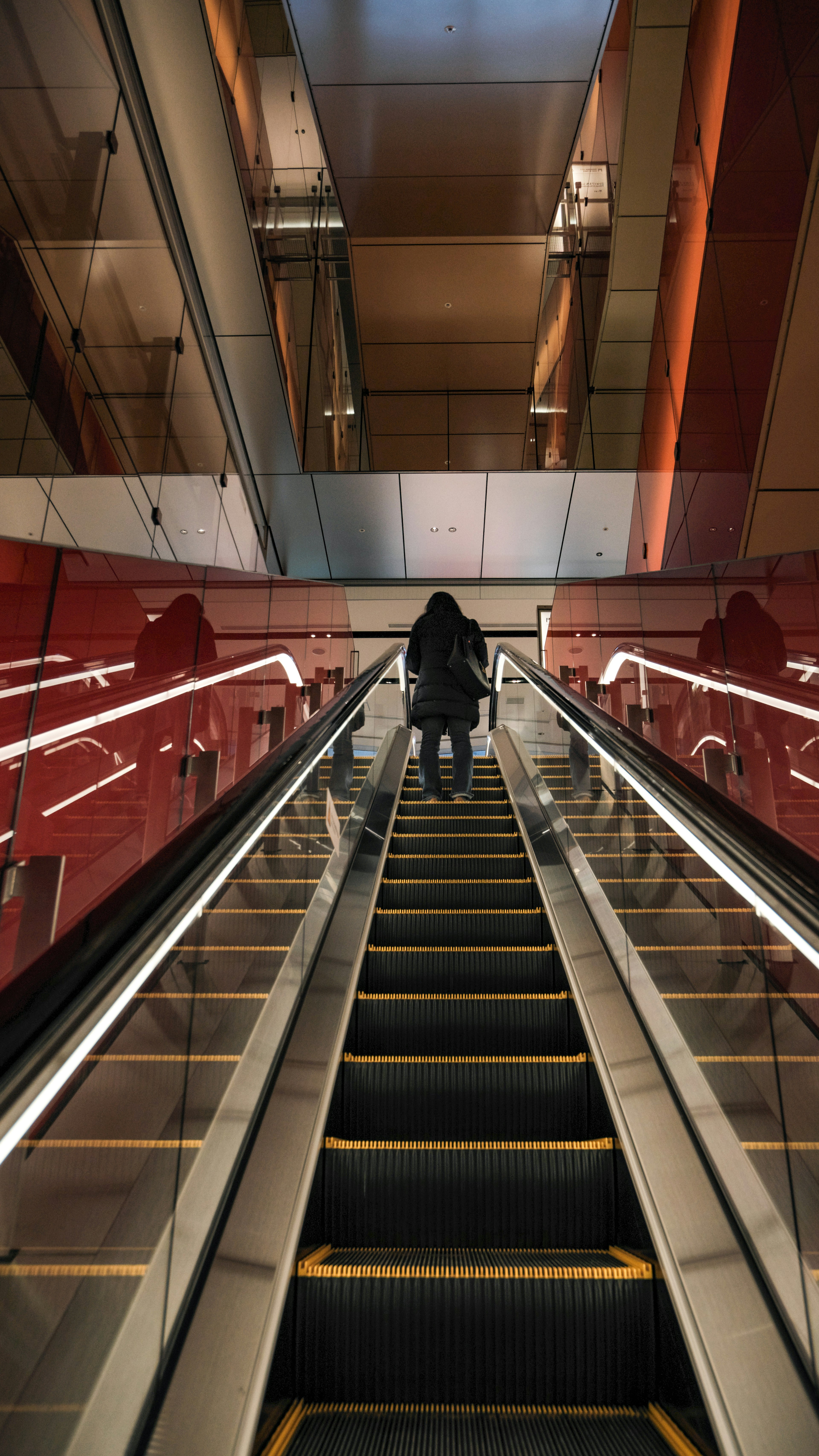 Persona subiendo una escalera mecánica con paredes rojas