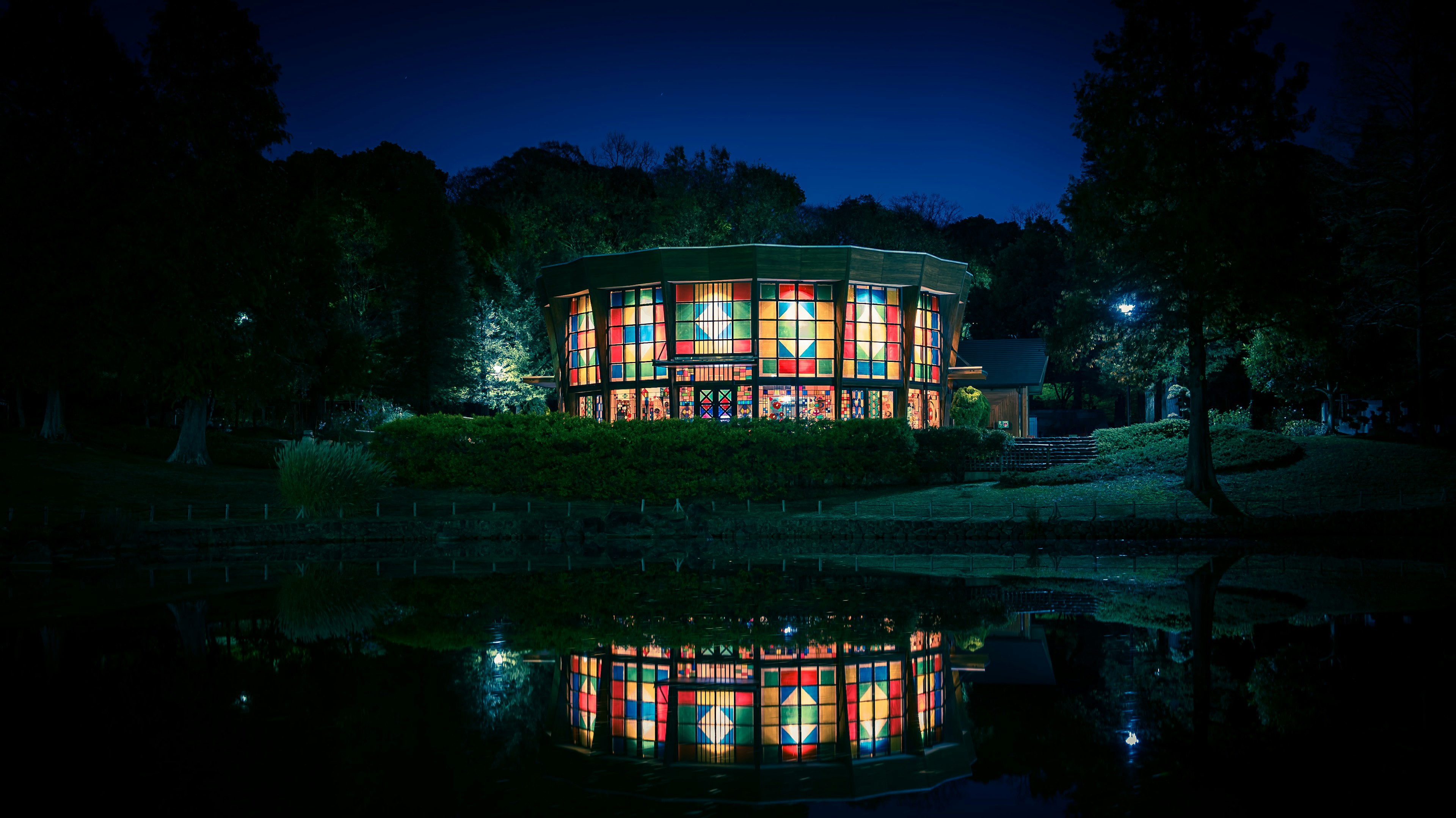 夜の公園にある美しいガラス張りの建物の反射