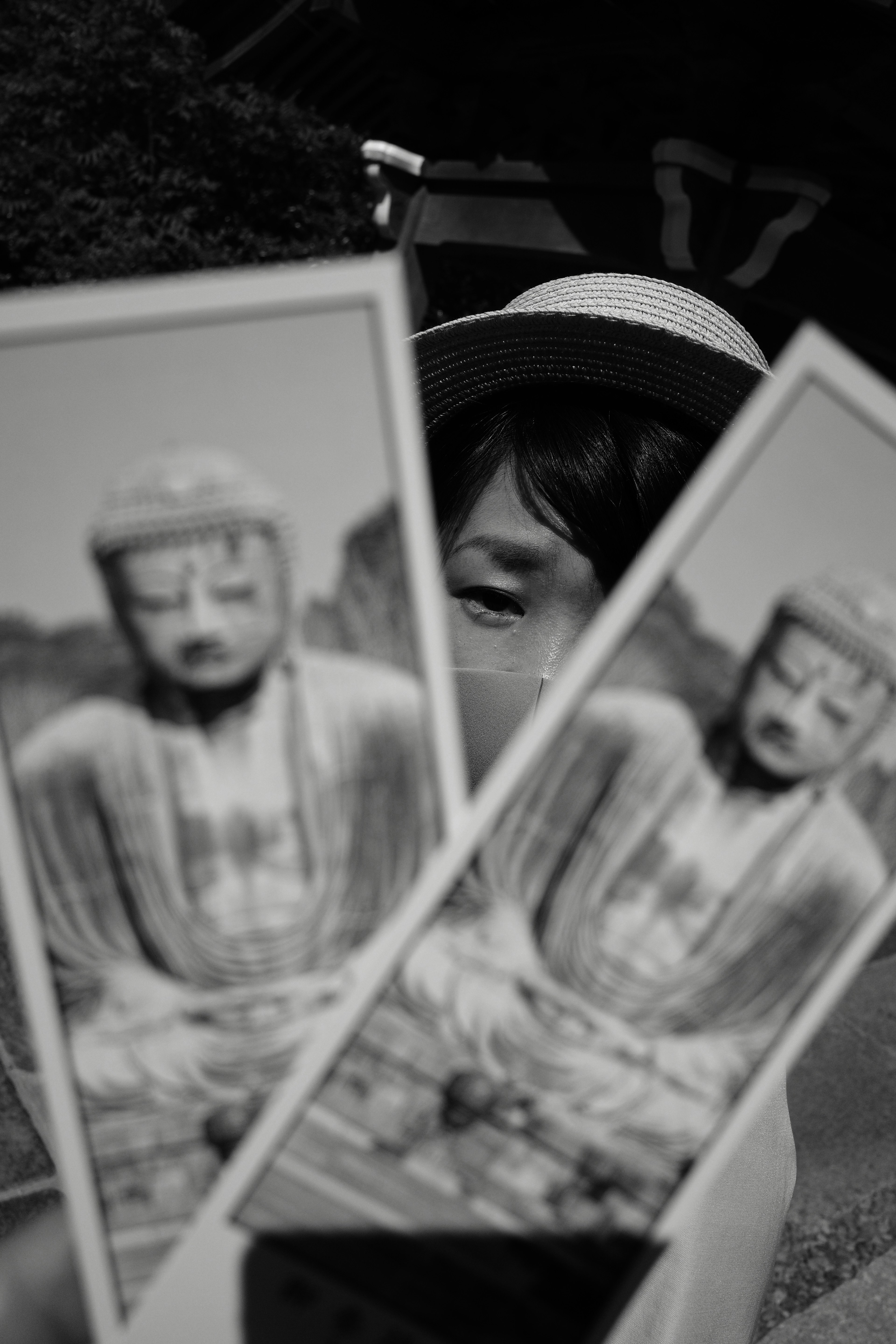 Una mujer sosteniendo fotografías de una estatua de Buda en blanco y negro