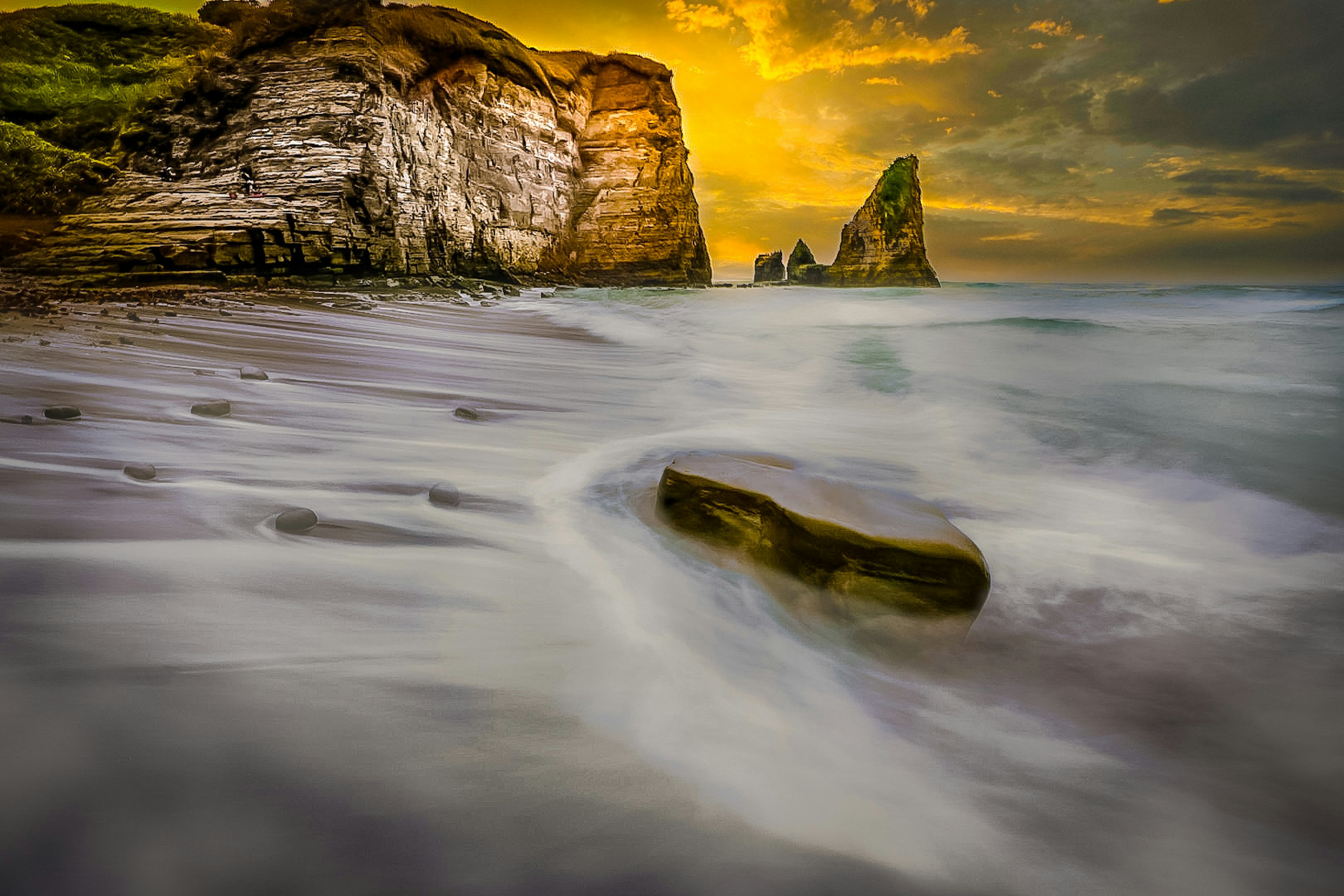 Coastal landscape at sunset featuring cliffs and gentle waves