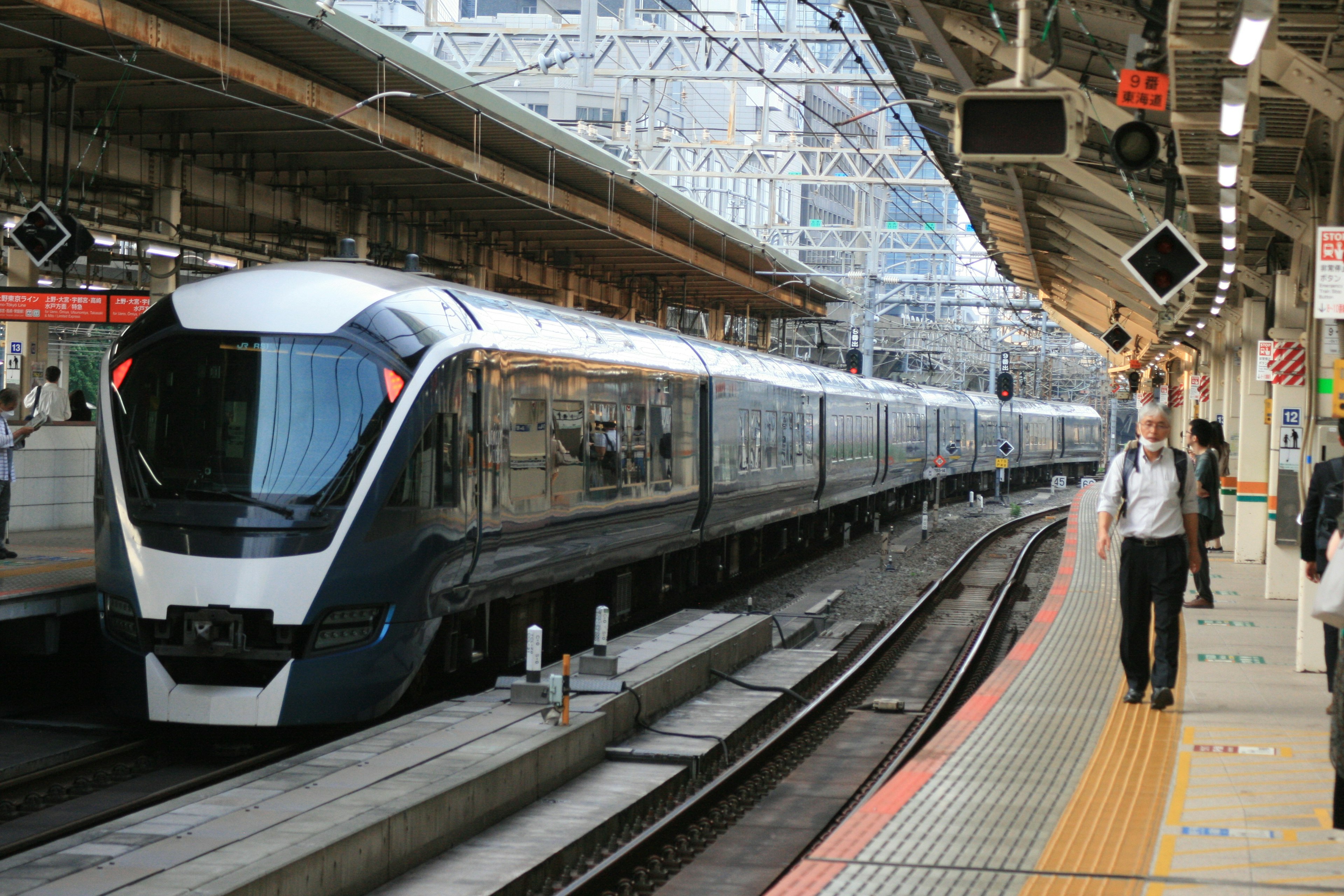 A modern train with a sleek design stopped at a busy station platform