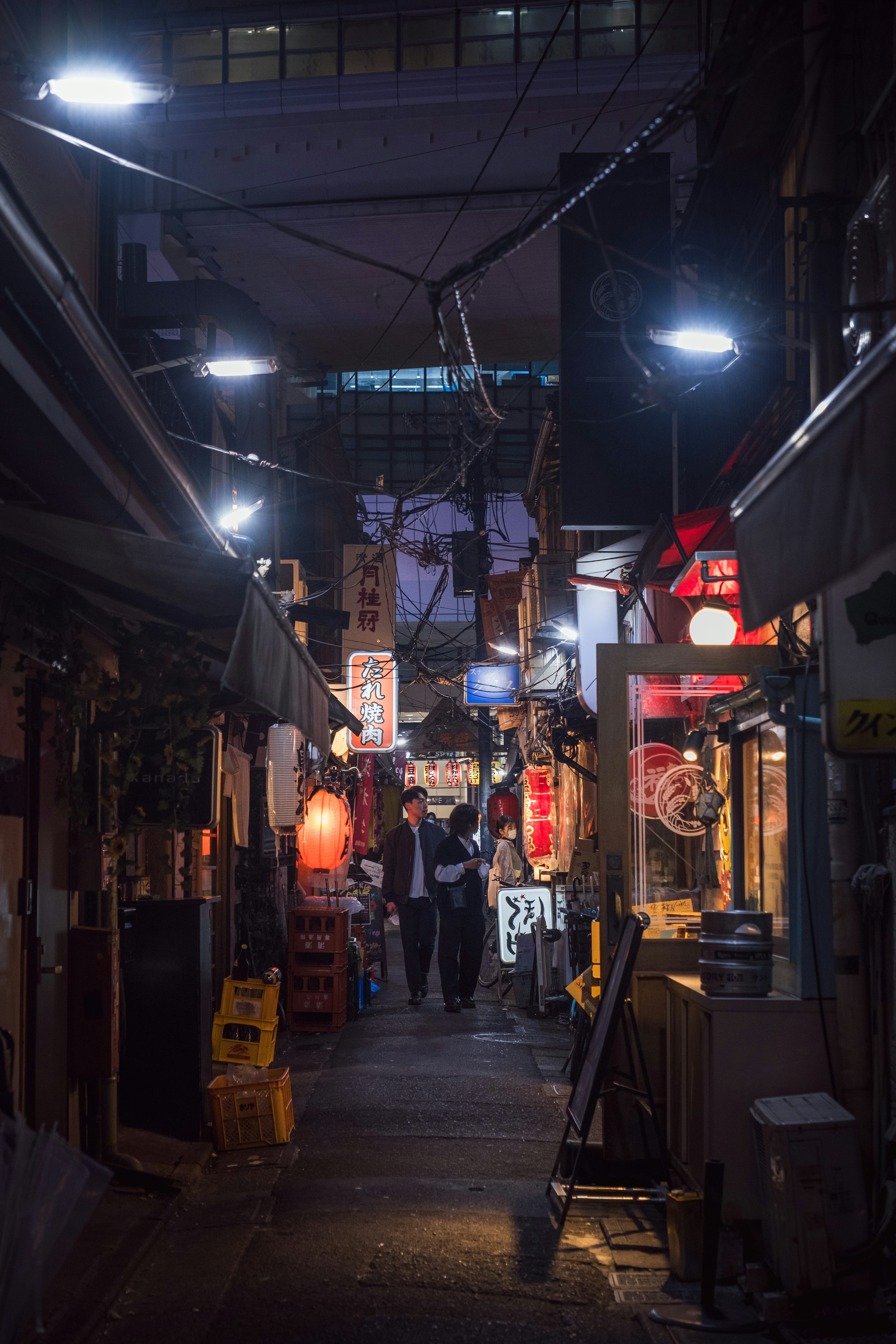 Escena nocturna de un callejón estrecho con puestos de comida iluminados