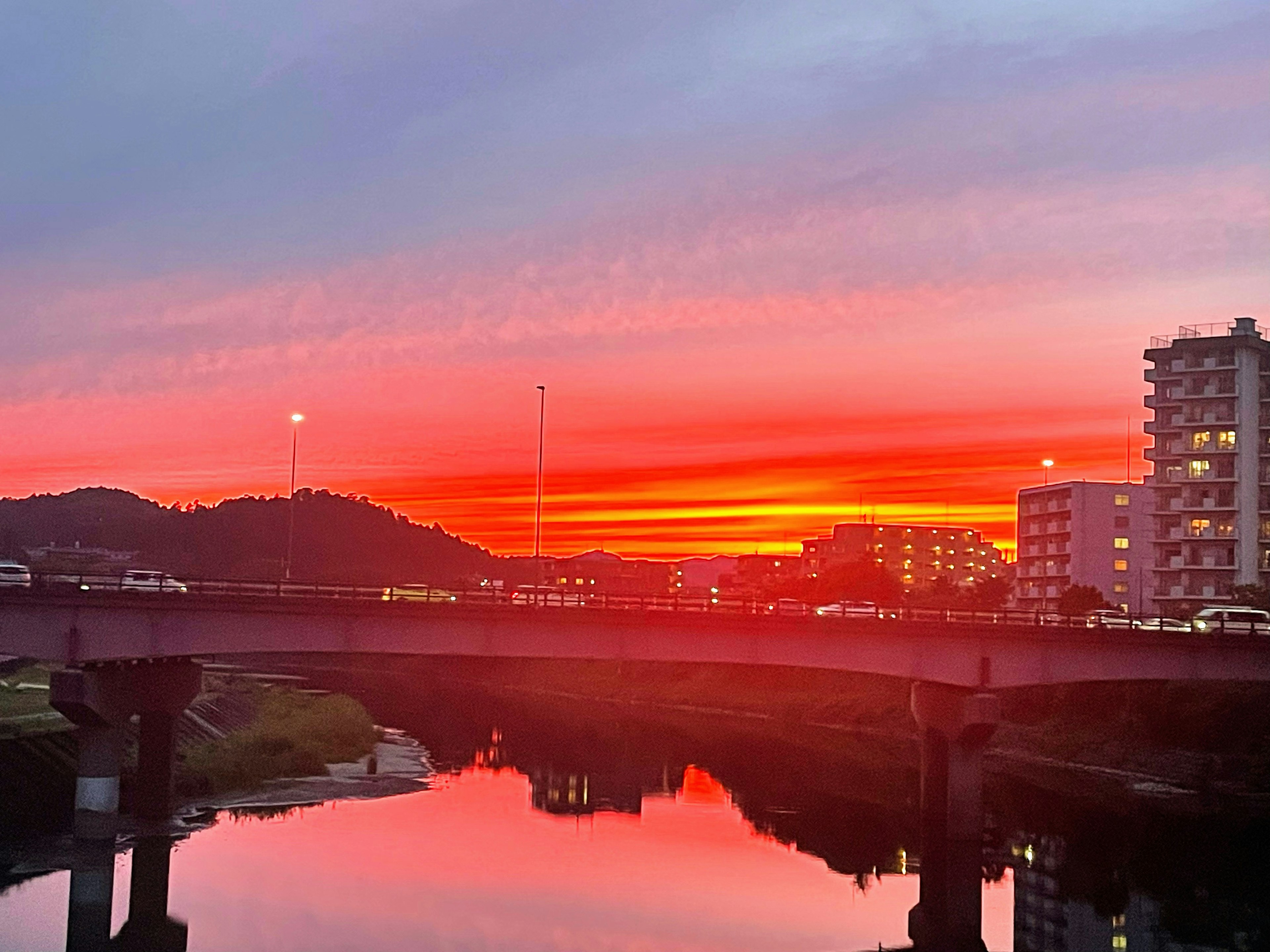 Wunderschöner Sonnenuntergang spiegelt sich in einem Fluss mit einer Brücke