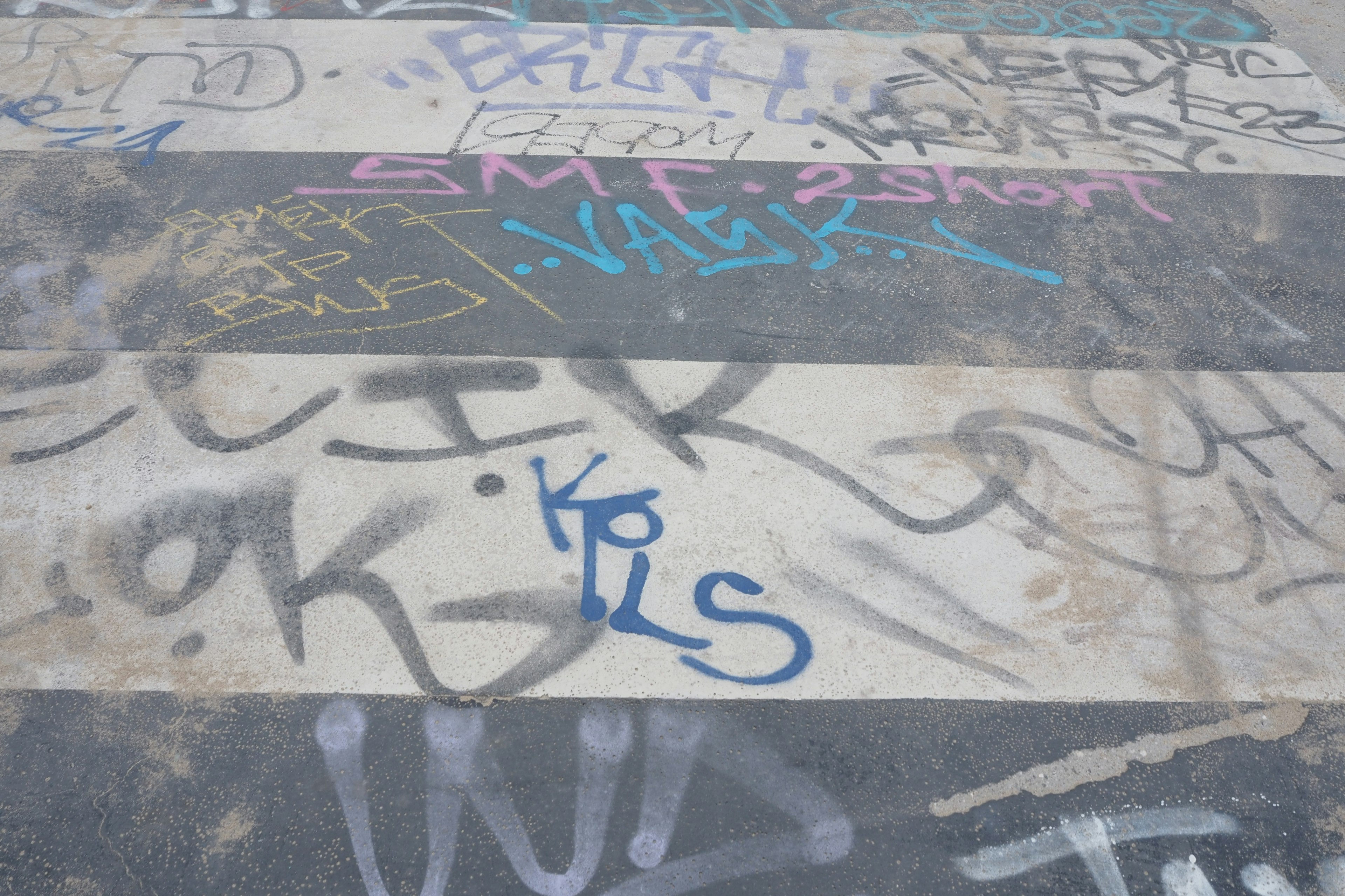 A street surface with various graffiti in multiple colors and styles