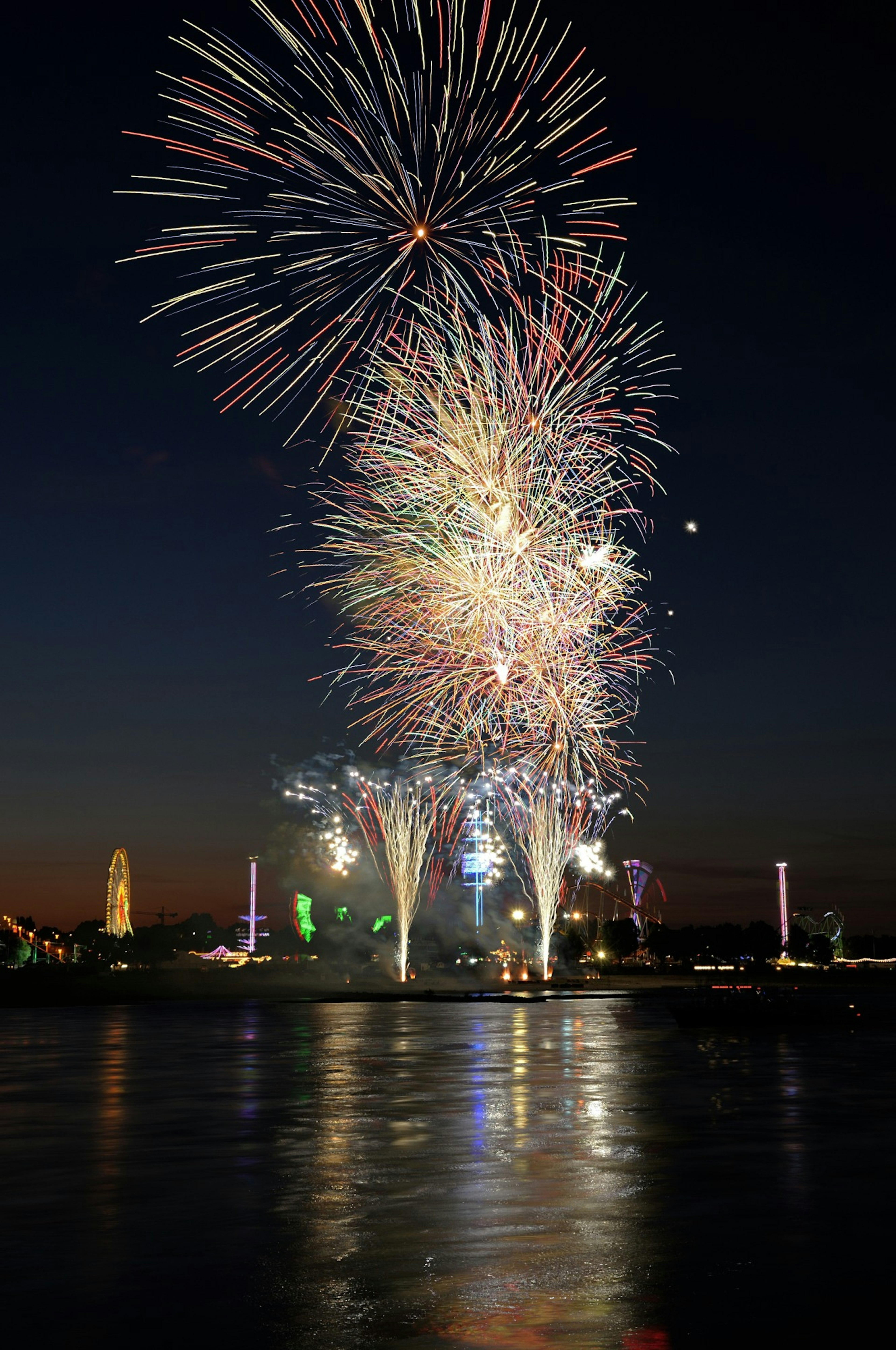 Espectáculo de fuegos artificiales coloridos sobre el agua por la noche