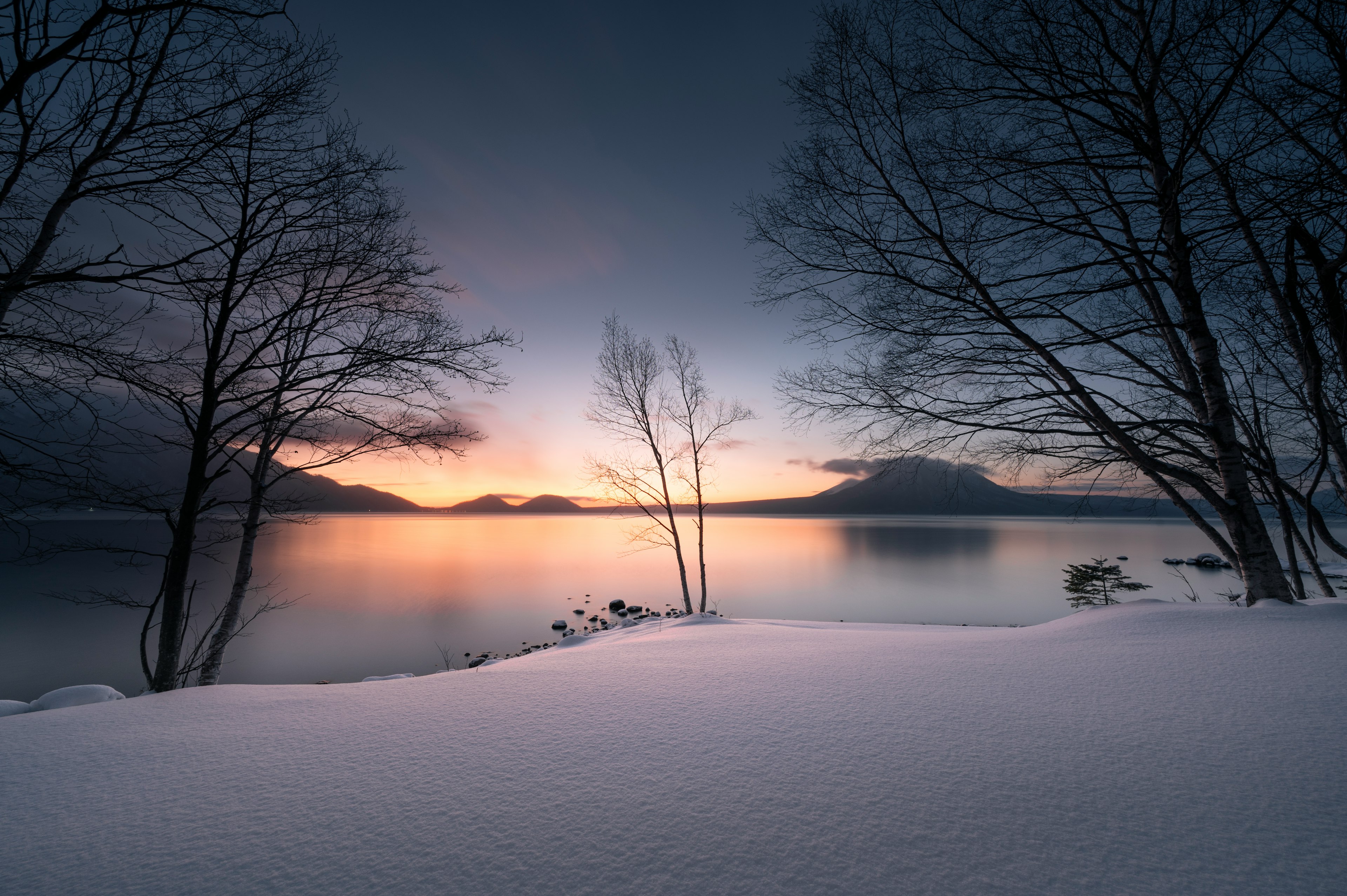 雪に覆われた湖の岸辺と夕焼けの景色