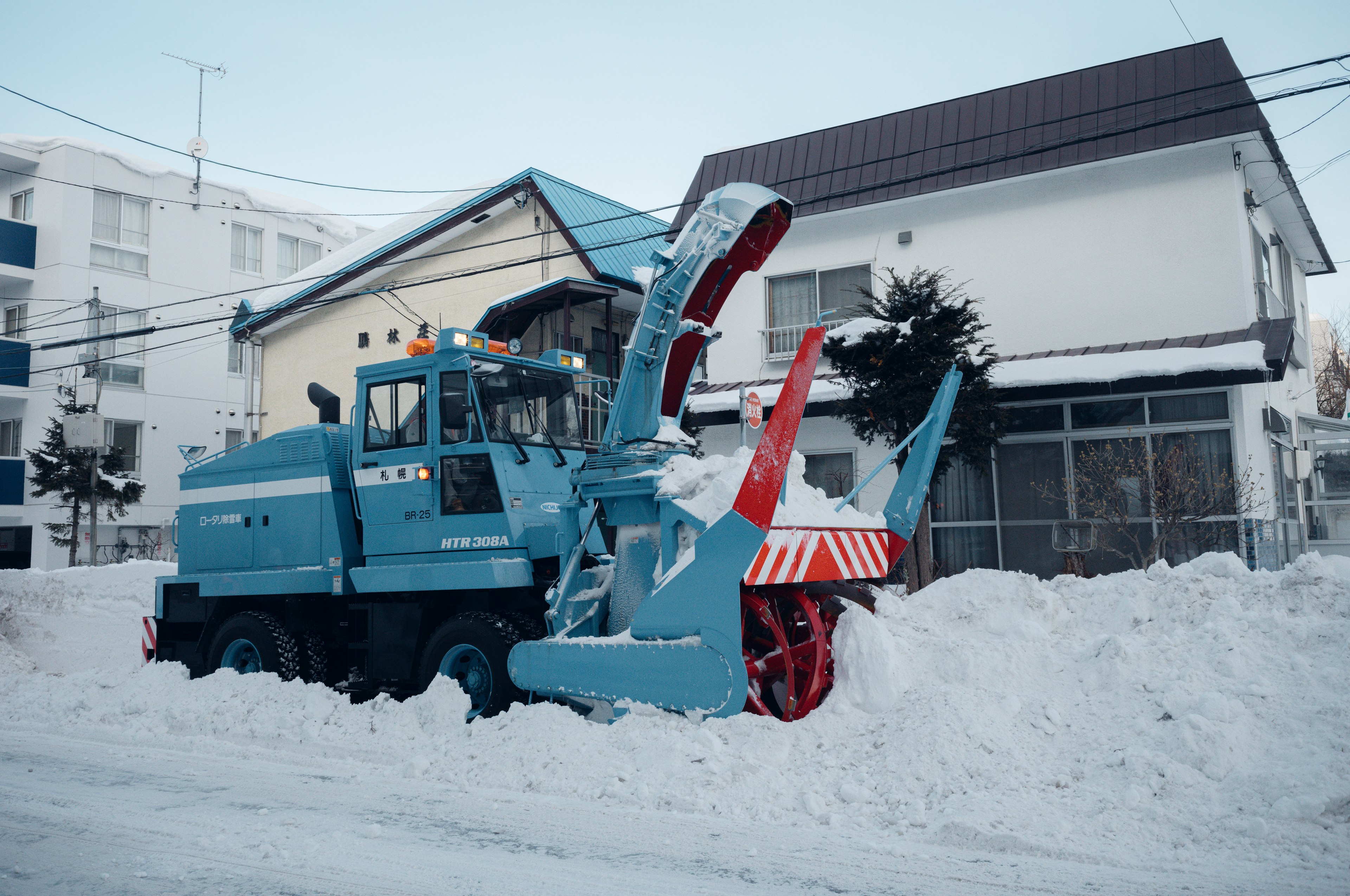 Un quitanieves azul está estacionado en una calle cubierta de nieve