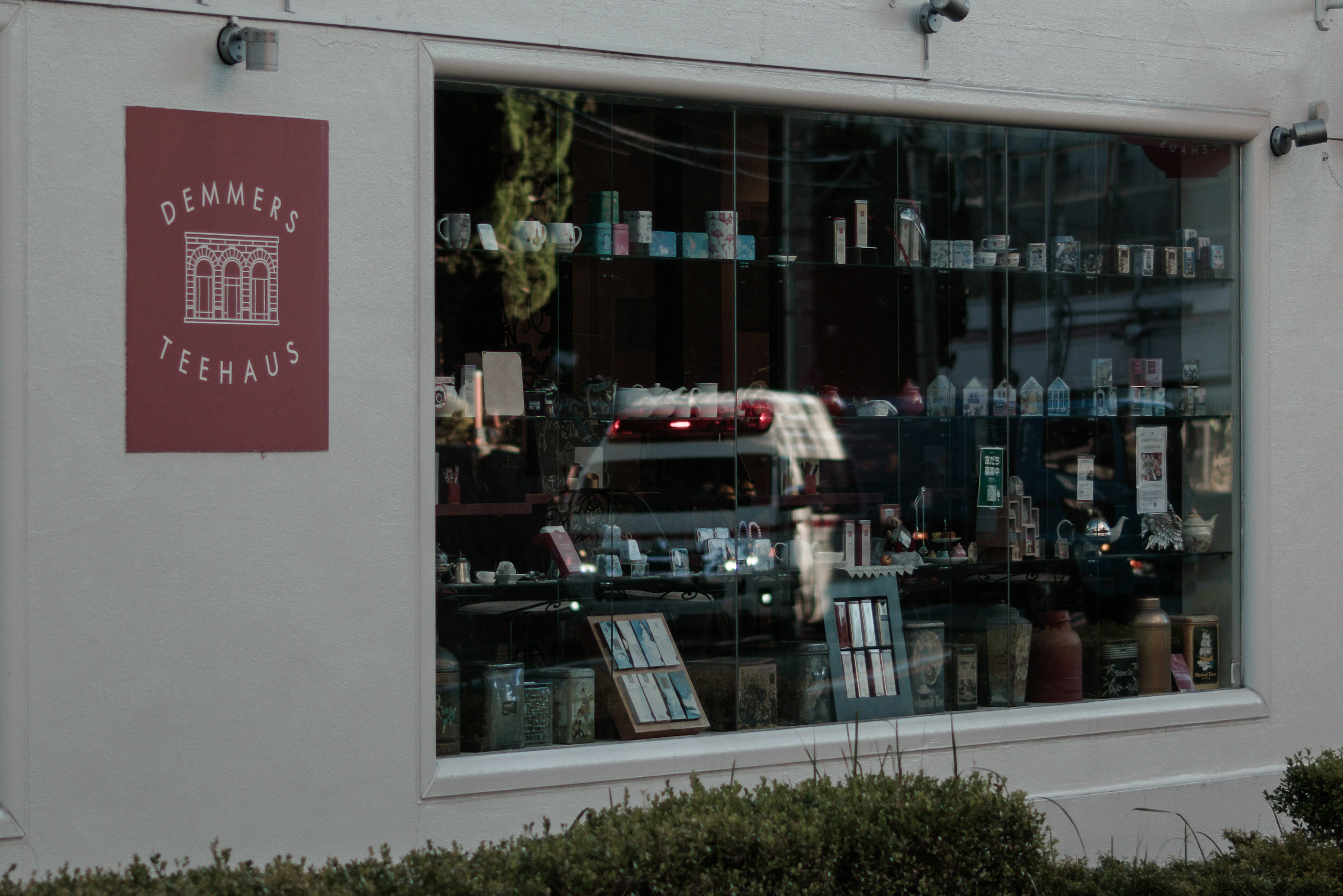 Storefront window displaying various products with the shop name on a red sign