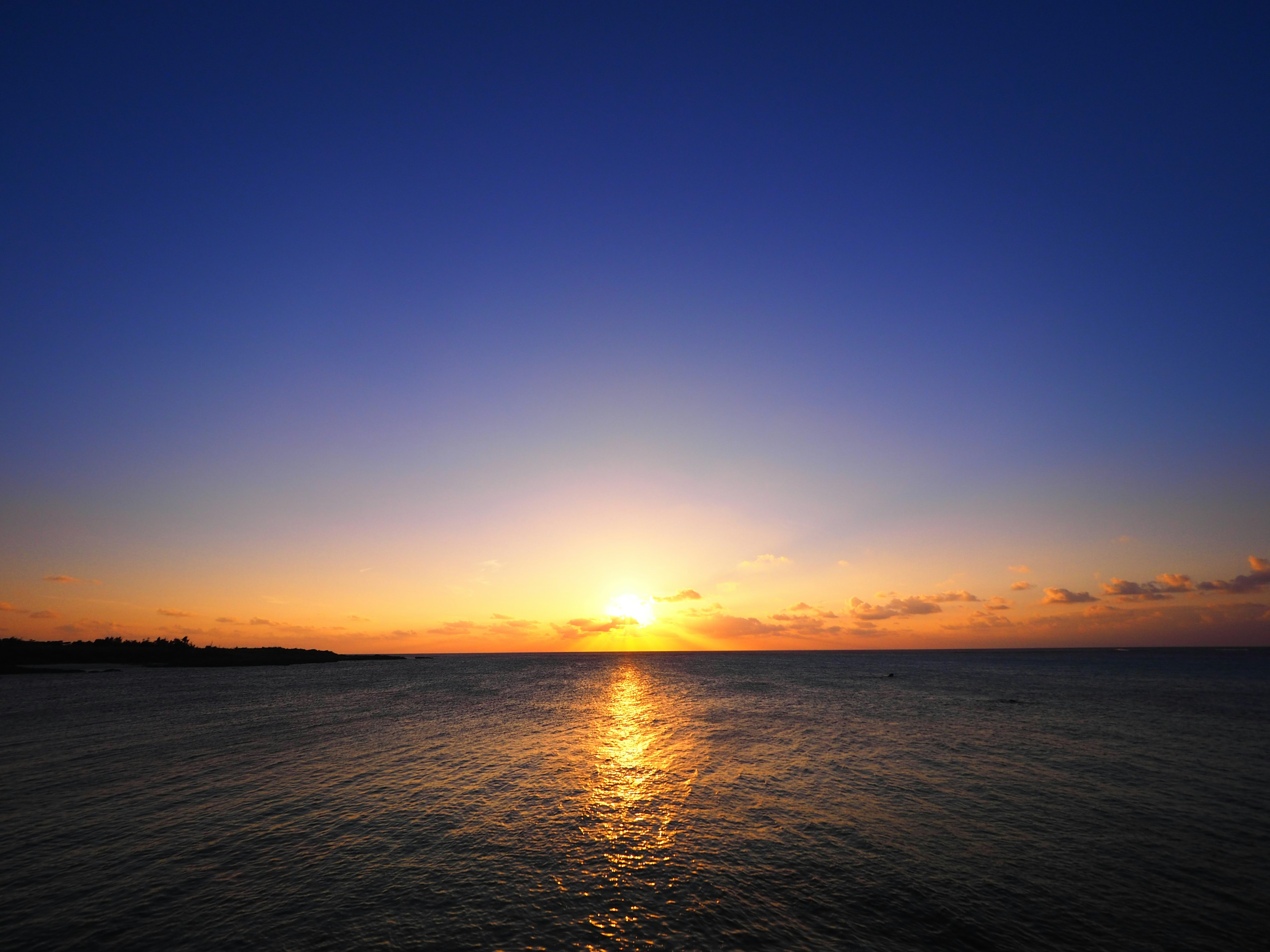 Hermoso paisaje con cielo azul y atardecer naranja reflejado en el mar