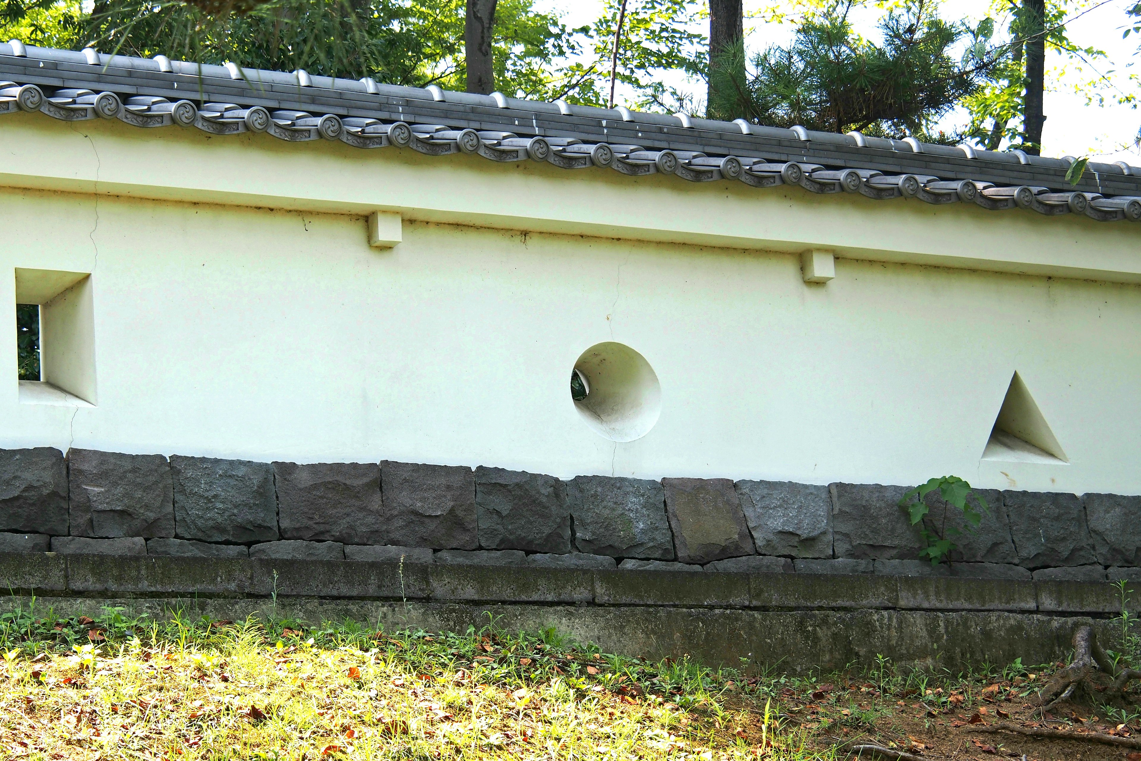 Exterior of a building with white walls featuring triangular and circular openings