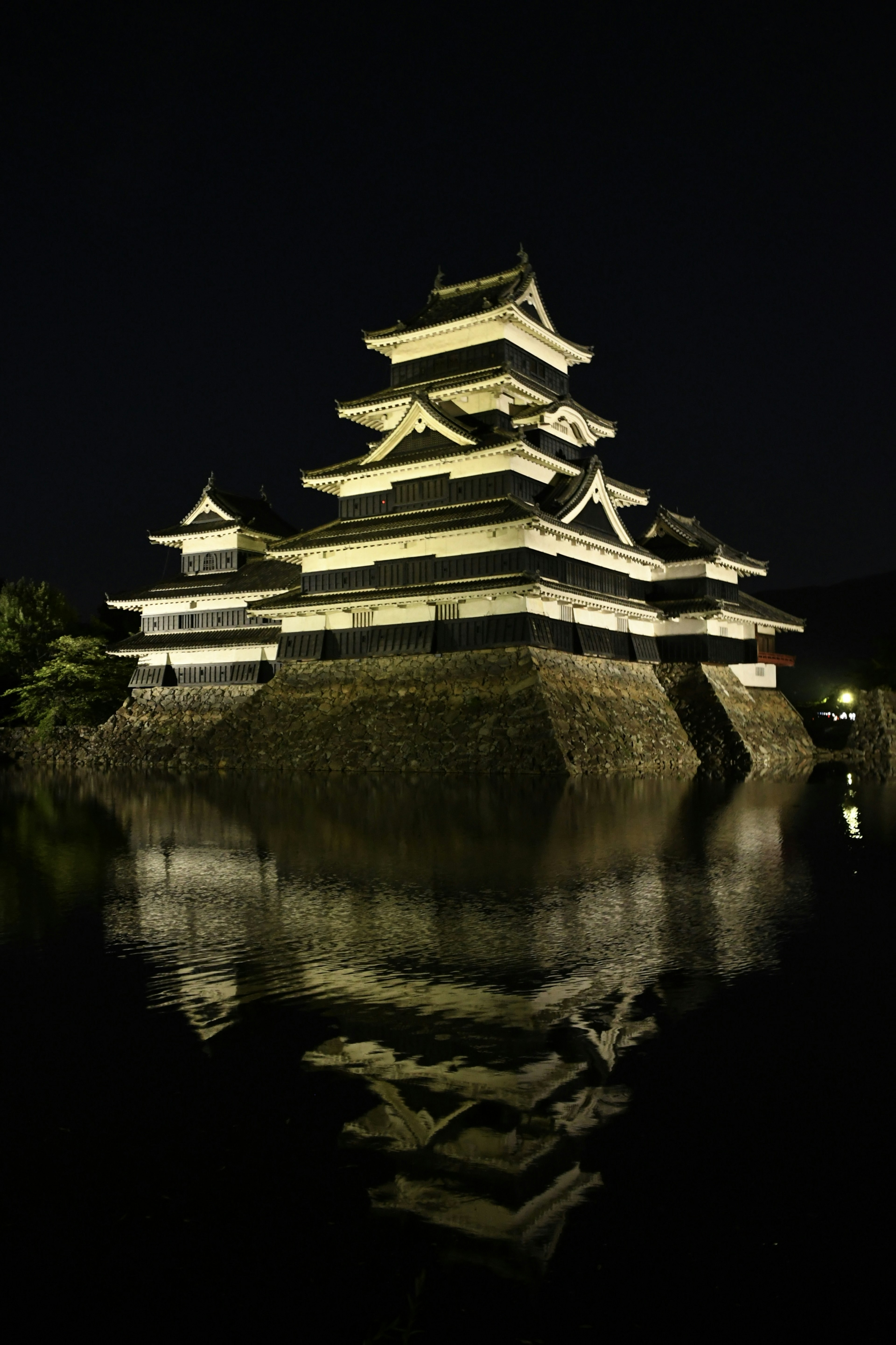 Vista notturna del castello di Matsumoto con riflesso nell'acqua