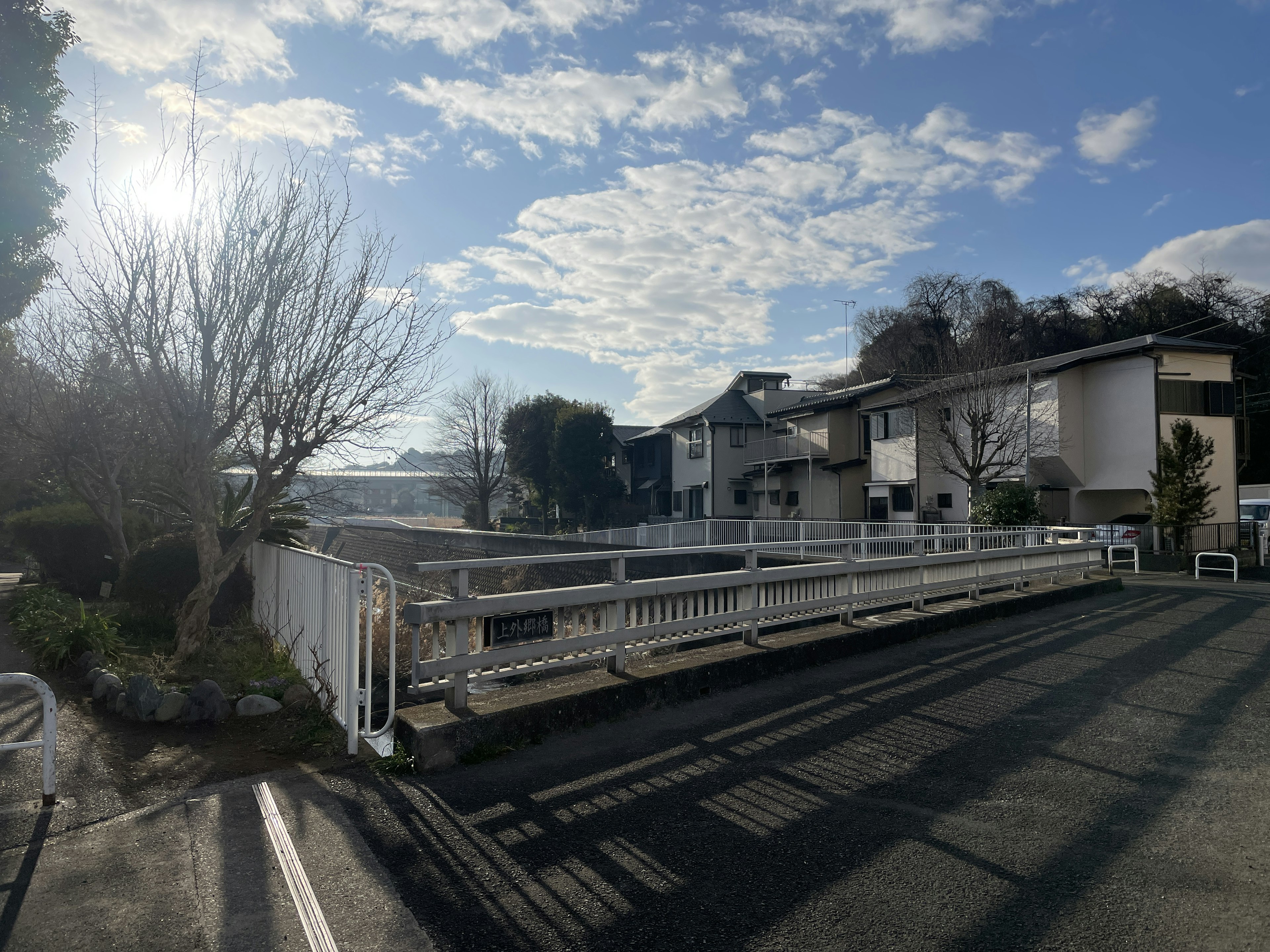 Una vista escénica de una zona residencial con un puente bajo un cielo azul y nubes blancas