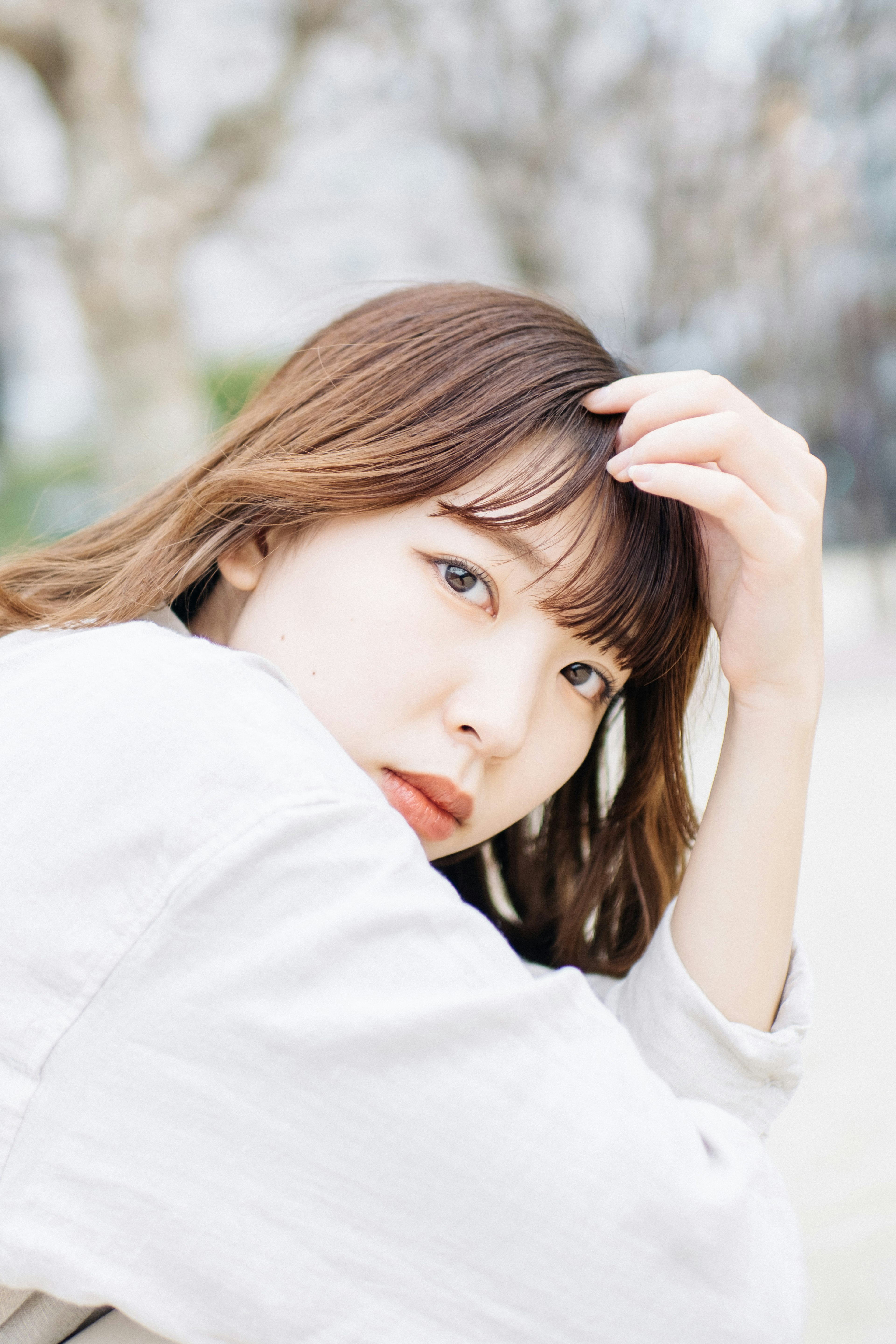 Portrait of a woman in a white outfit touching her hair