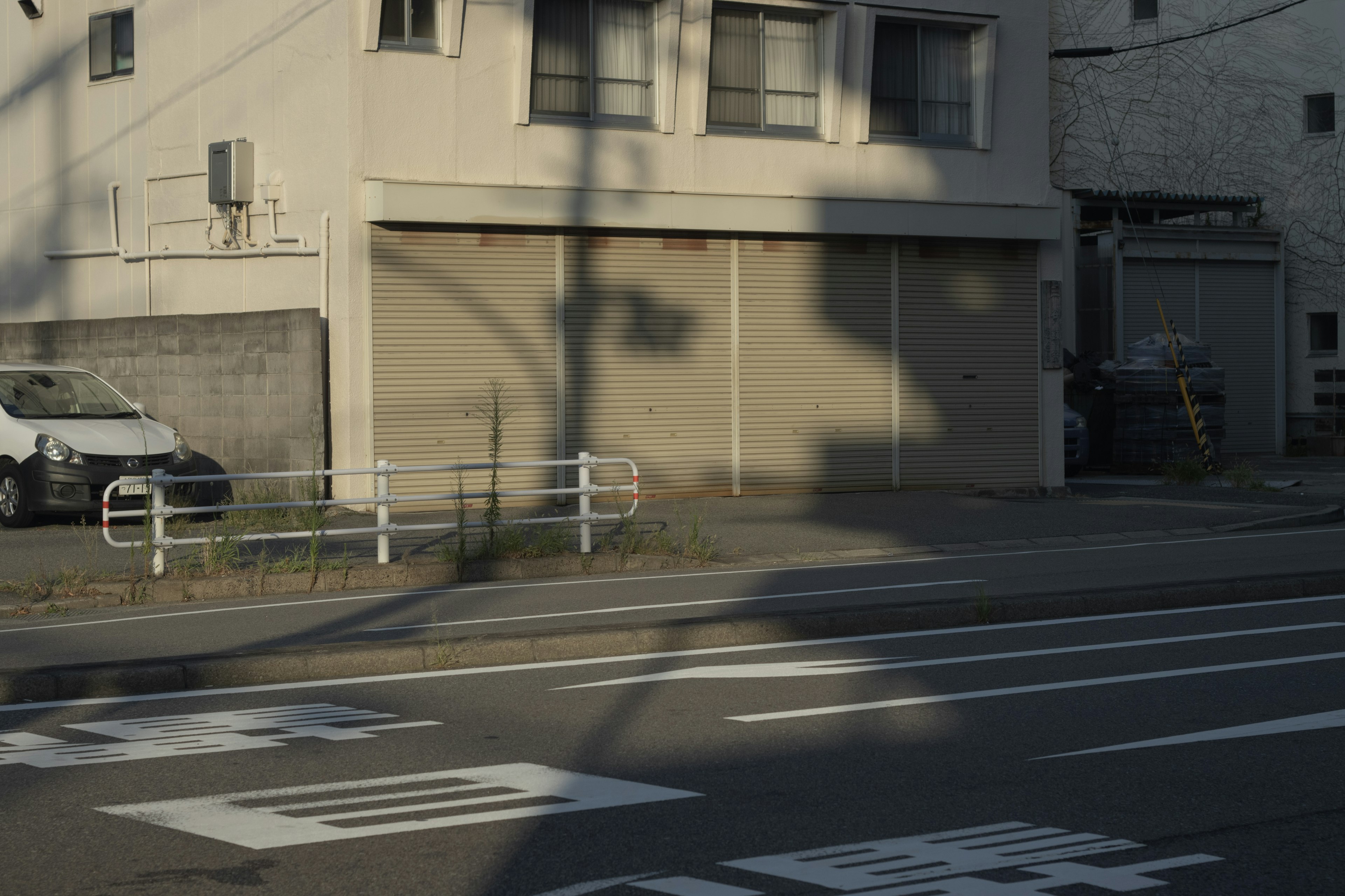 Foto einer Straße mit Schatten, die auf ein Gebäude fallen