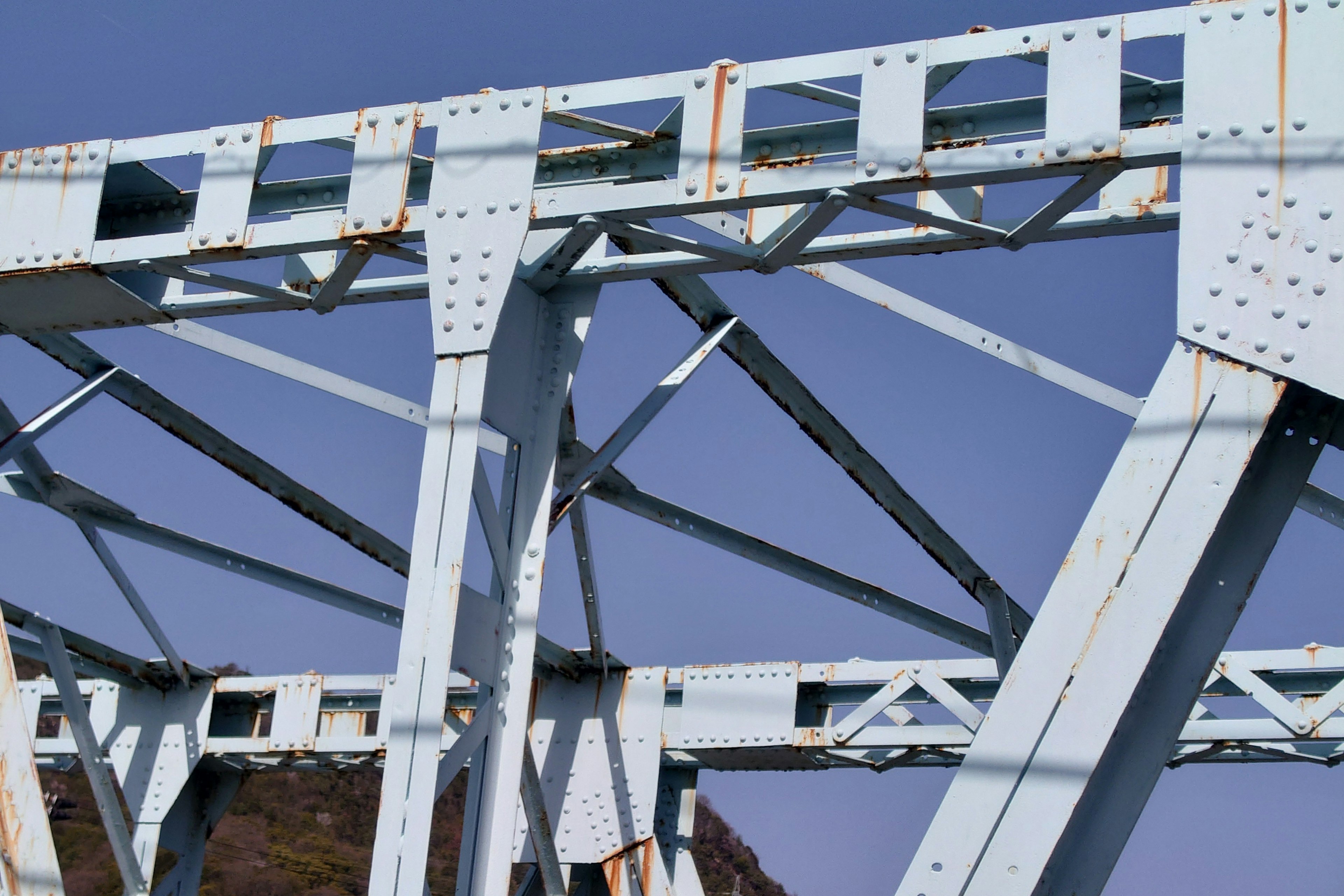 Detail struktur jembatan logam biru di latar belakang langit cerah