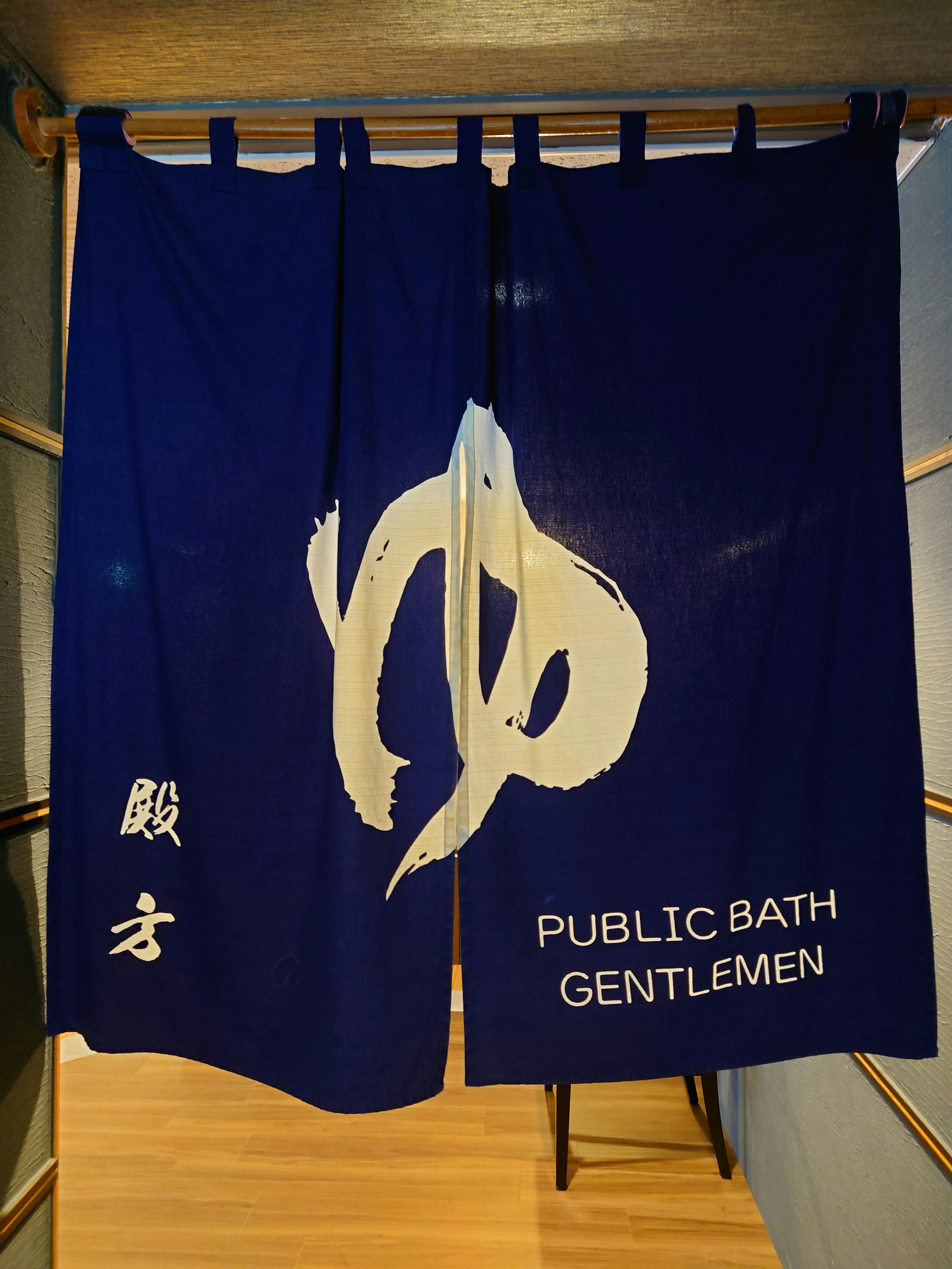 파란 노렌에 한자 '湯'와 'PUBLIC BATH GENTLEMEN' 글씨가 적혀있음