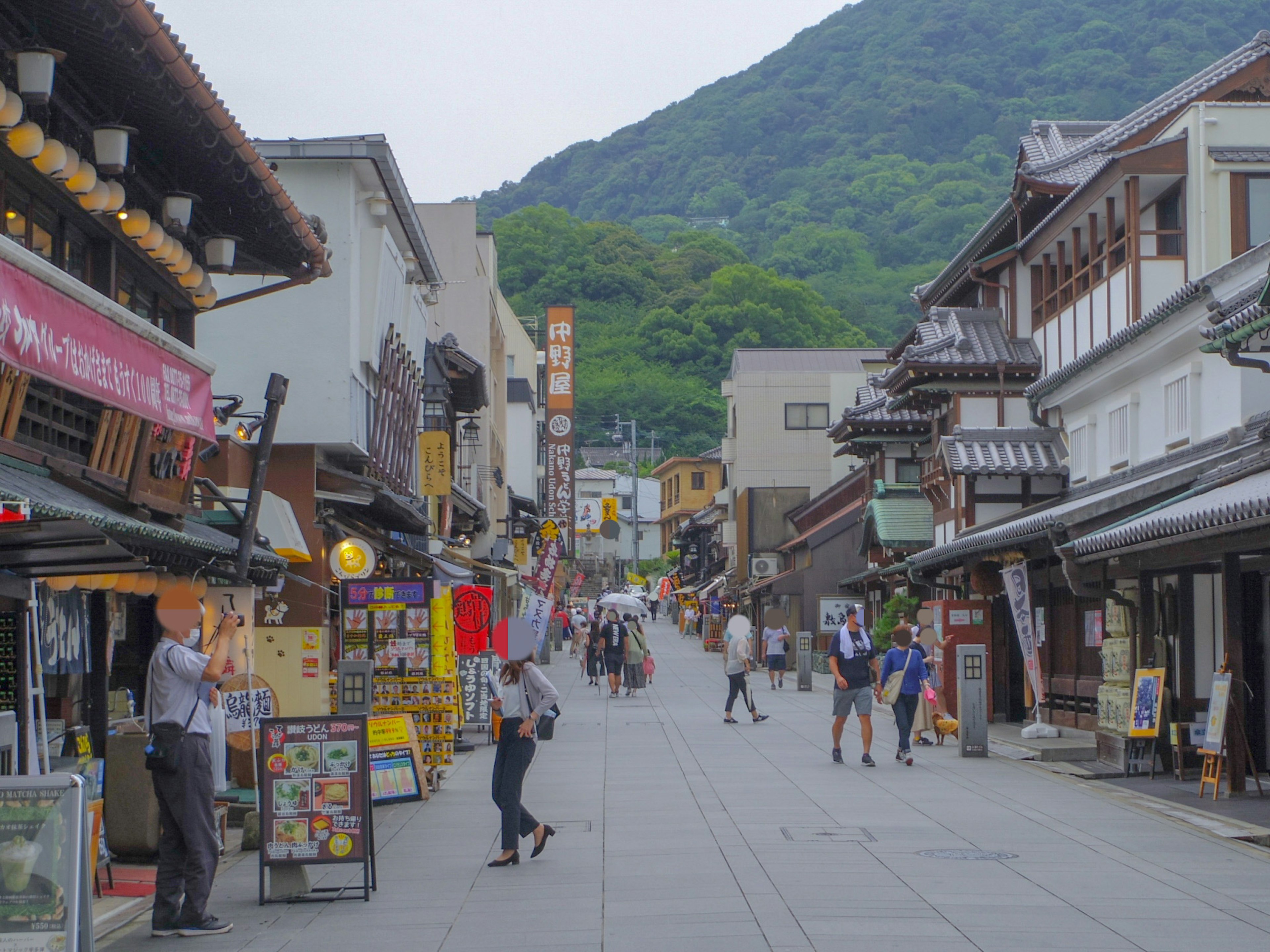 People walking in a traditional Japanese shopping street with a mountain backdrop