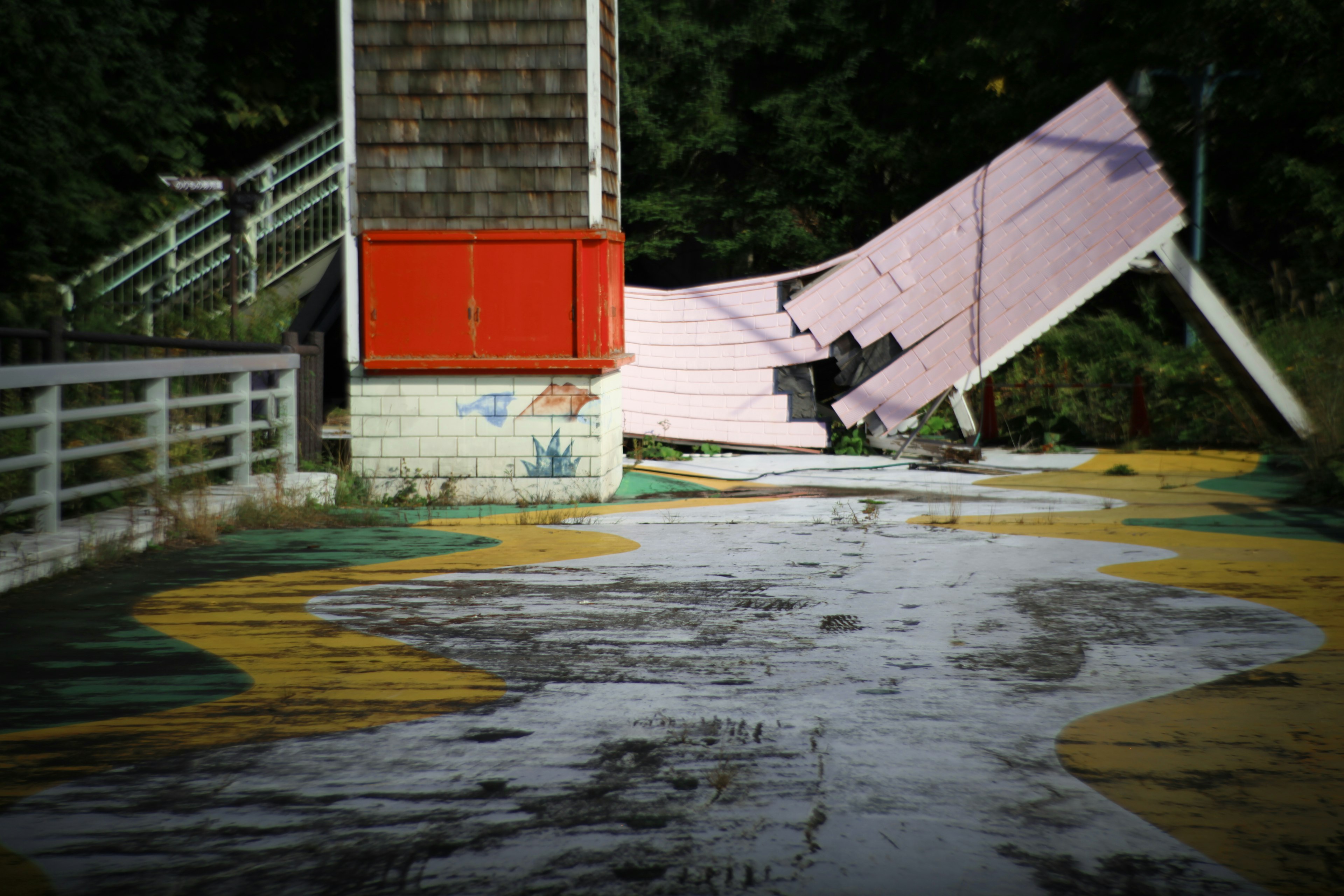 Parte de un parque de atracciones abandonado con un edificio colapsado y un suelo colorido