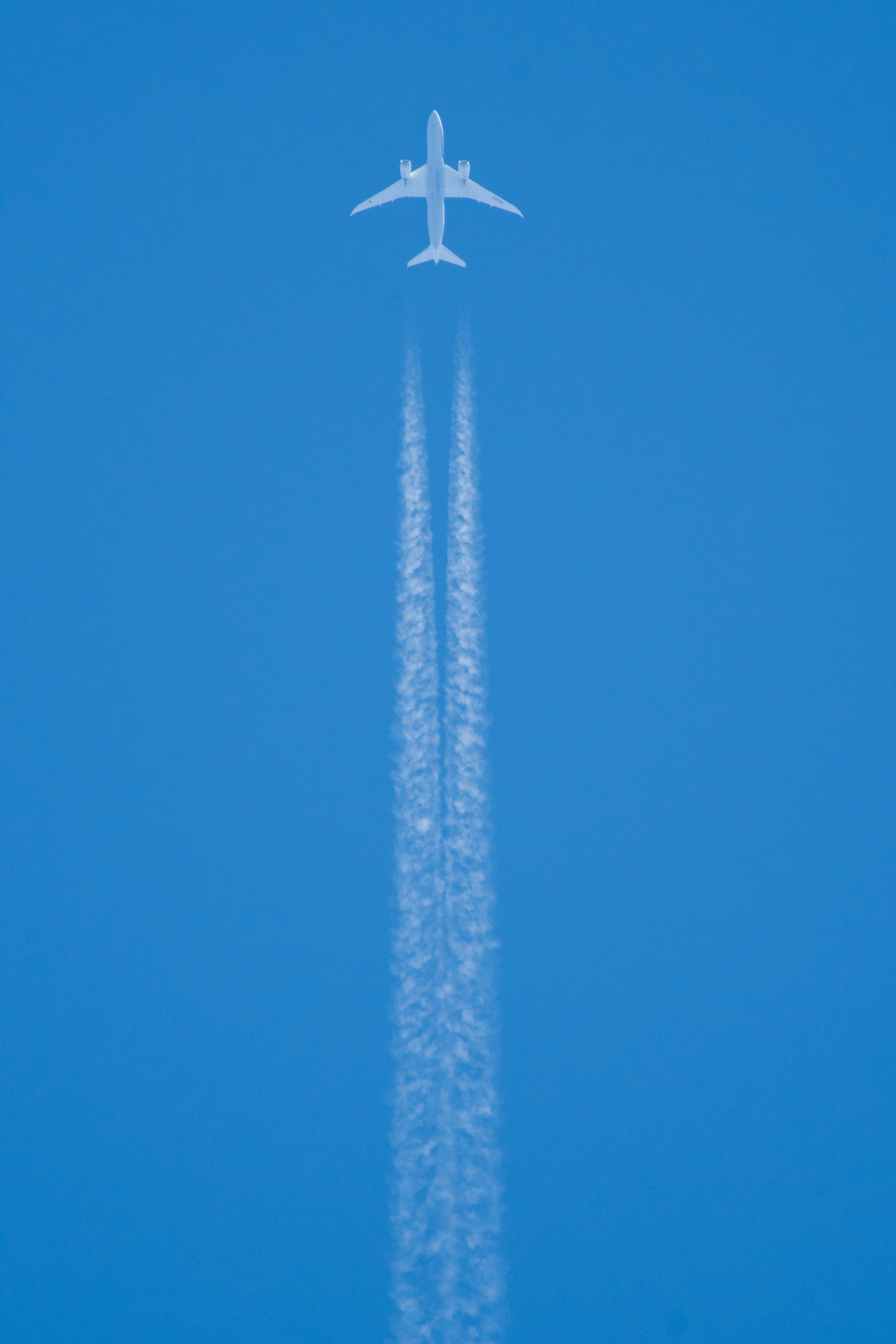 Un avión volando en un cielo azul claro dejando una estela blanca