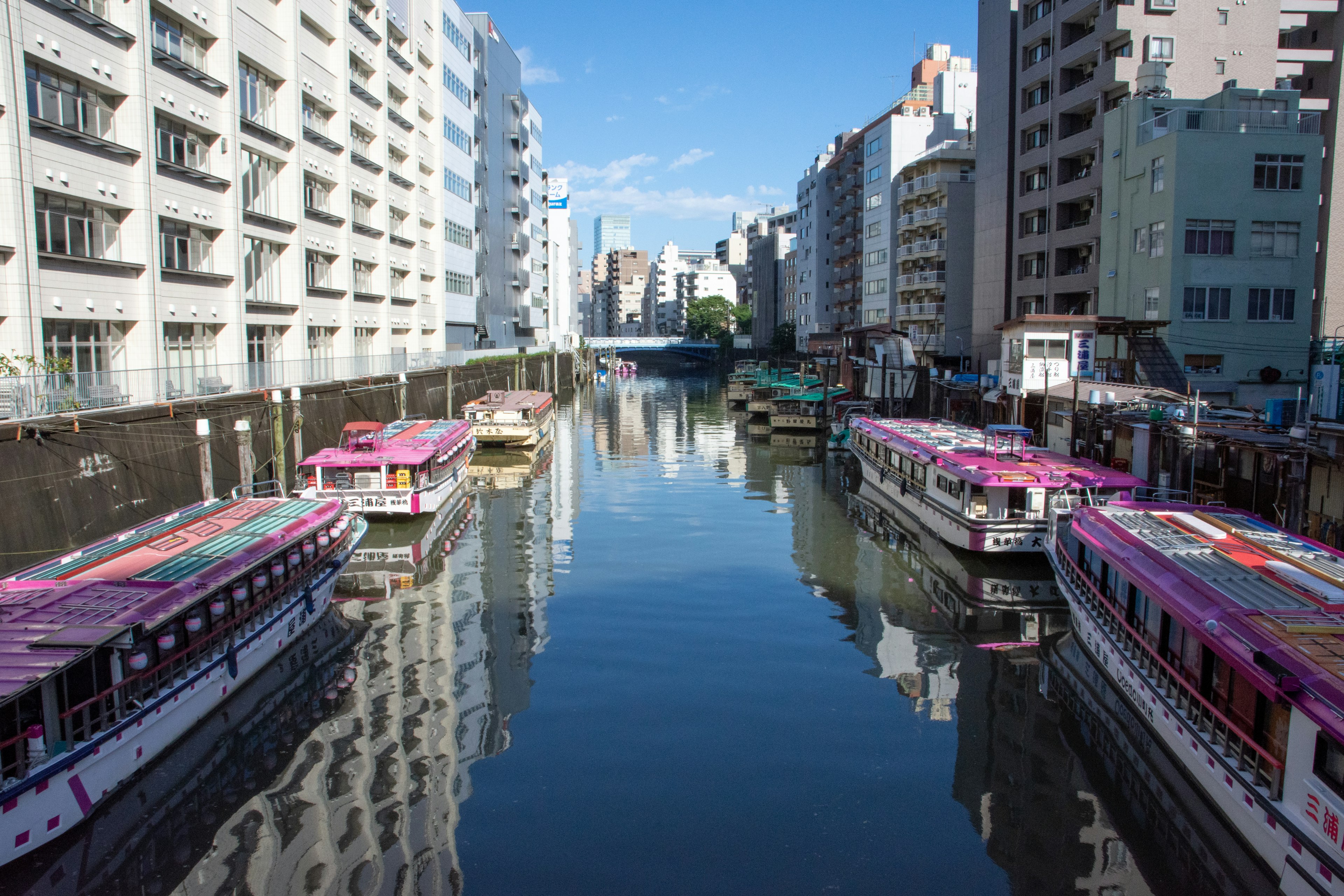 Botes coloridos alineados a lo largo de un canal con edificios modernos