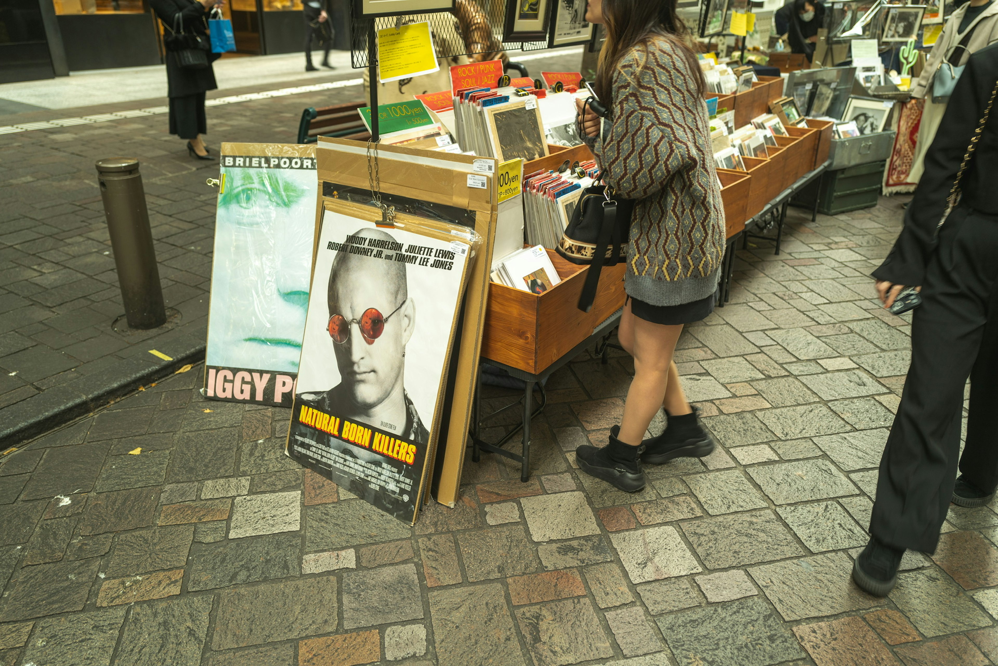 Mujer eligiendo libros en una librería callejera con un cartel