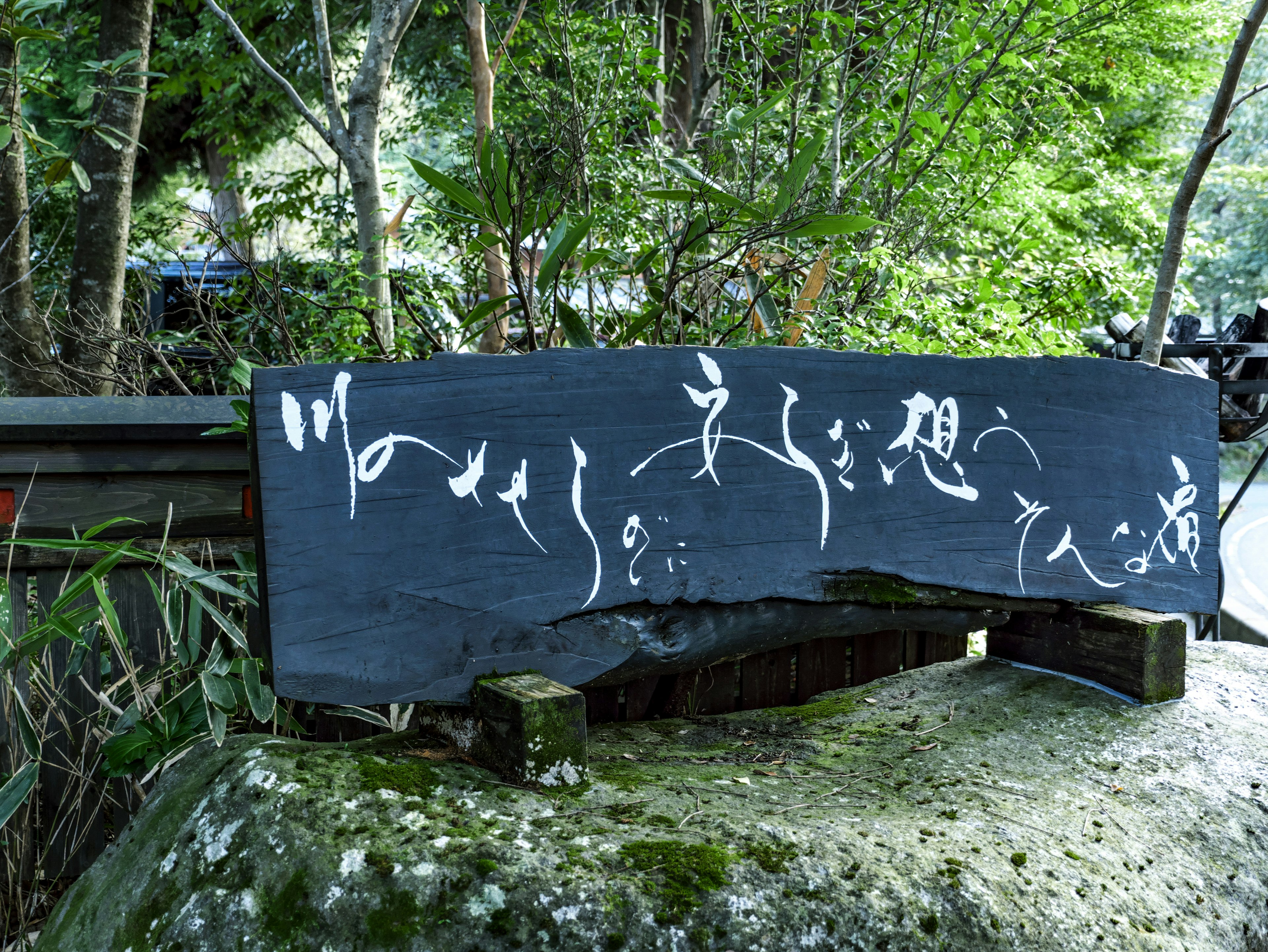 Black stone sign with white calligraphy in a natural setting