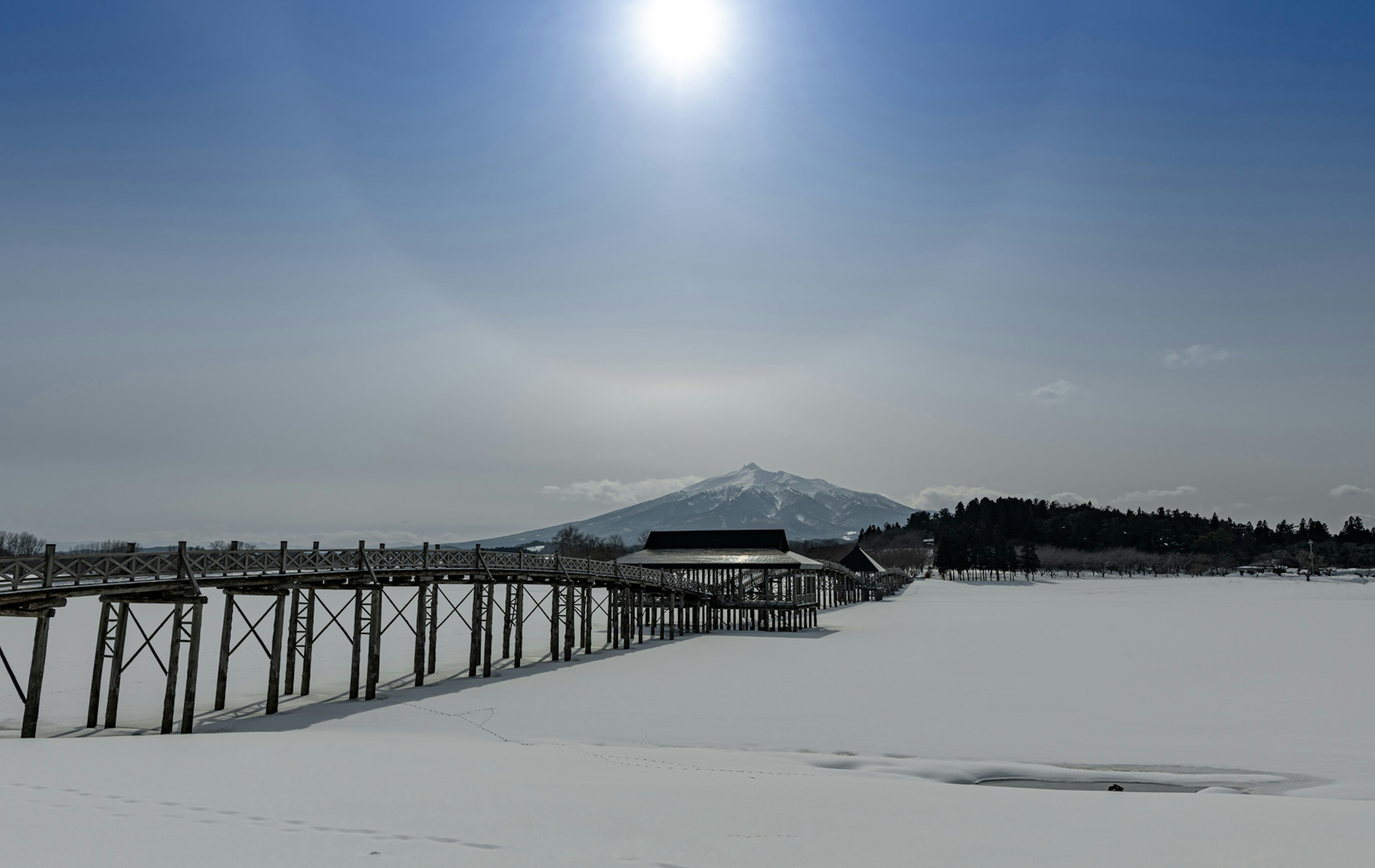 Sun shining over a snowy landscape with a distant mountain