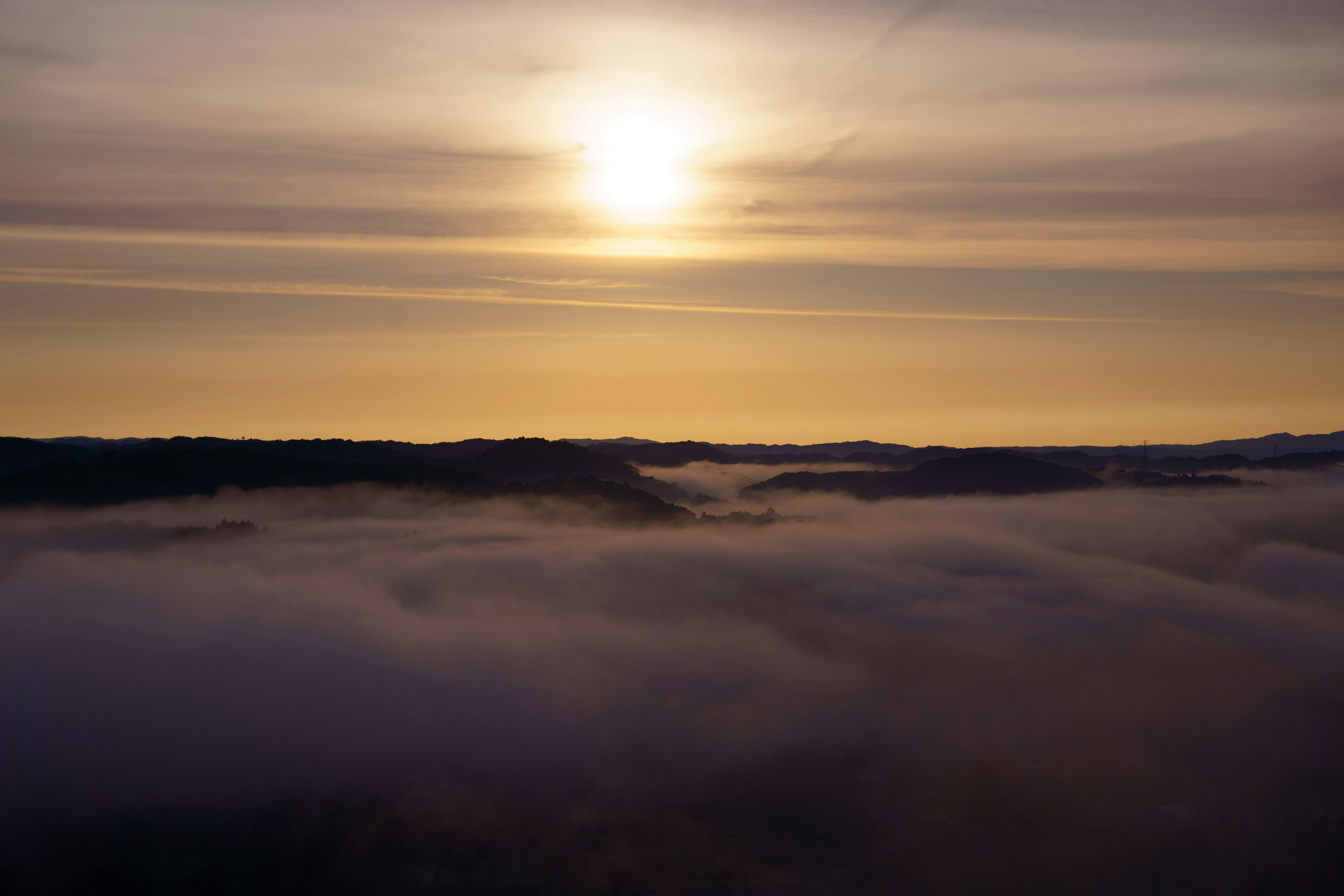 Sunrise over misty hills with soft clouds