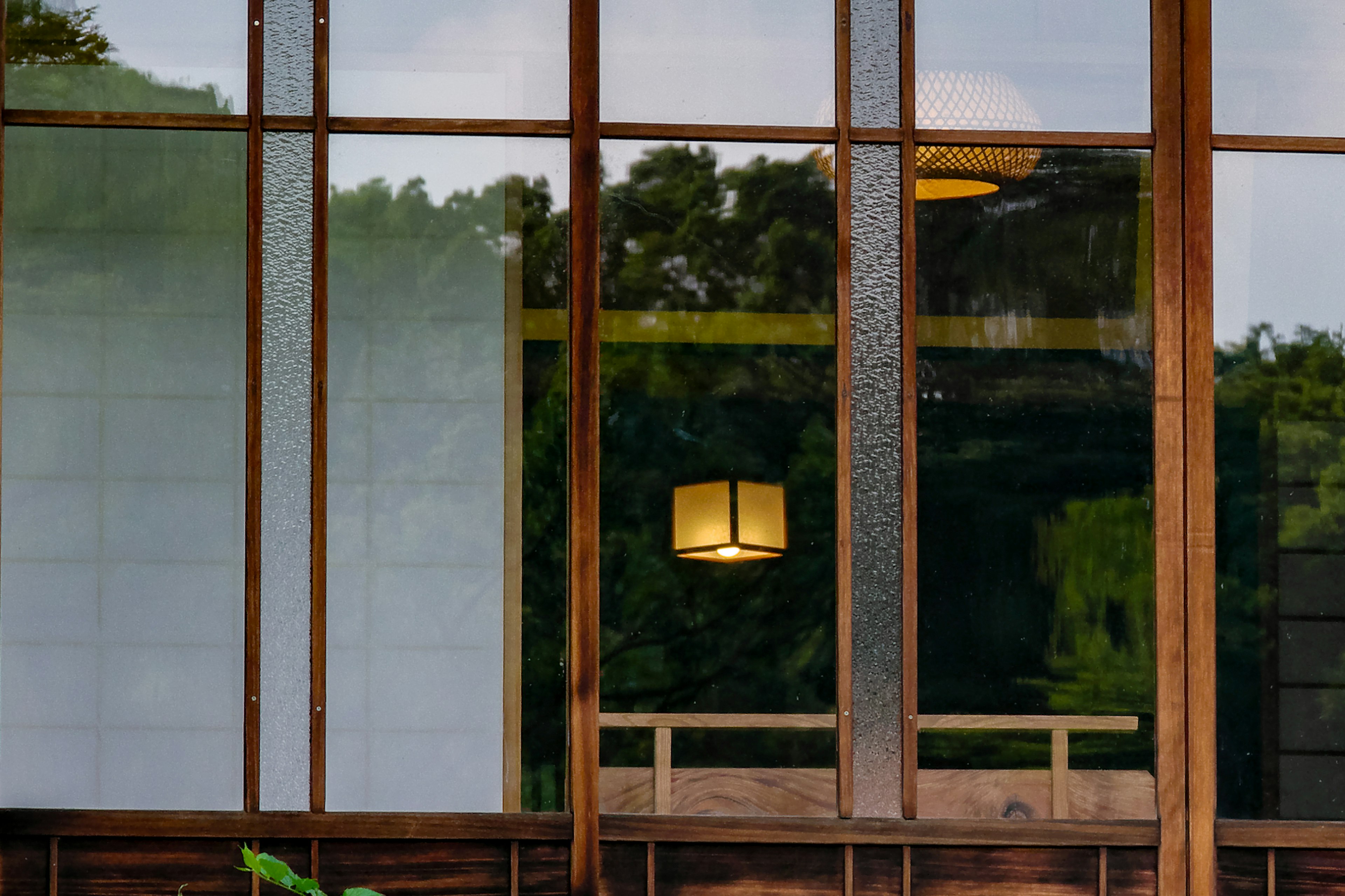 Fenster eines Holzgebäudes mit grünem Landschaftsbild und Licht