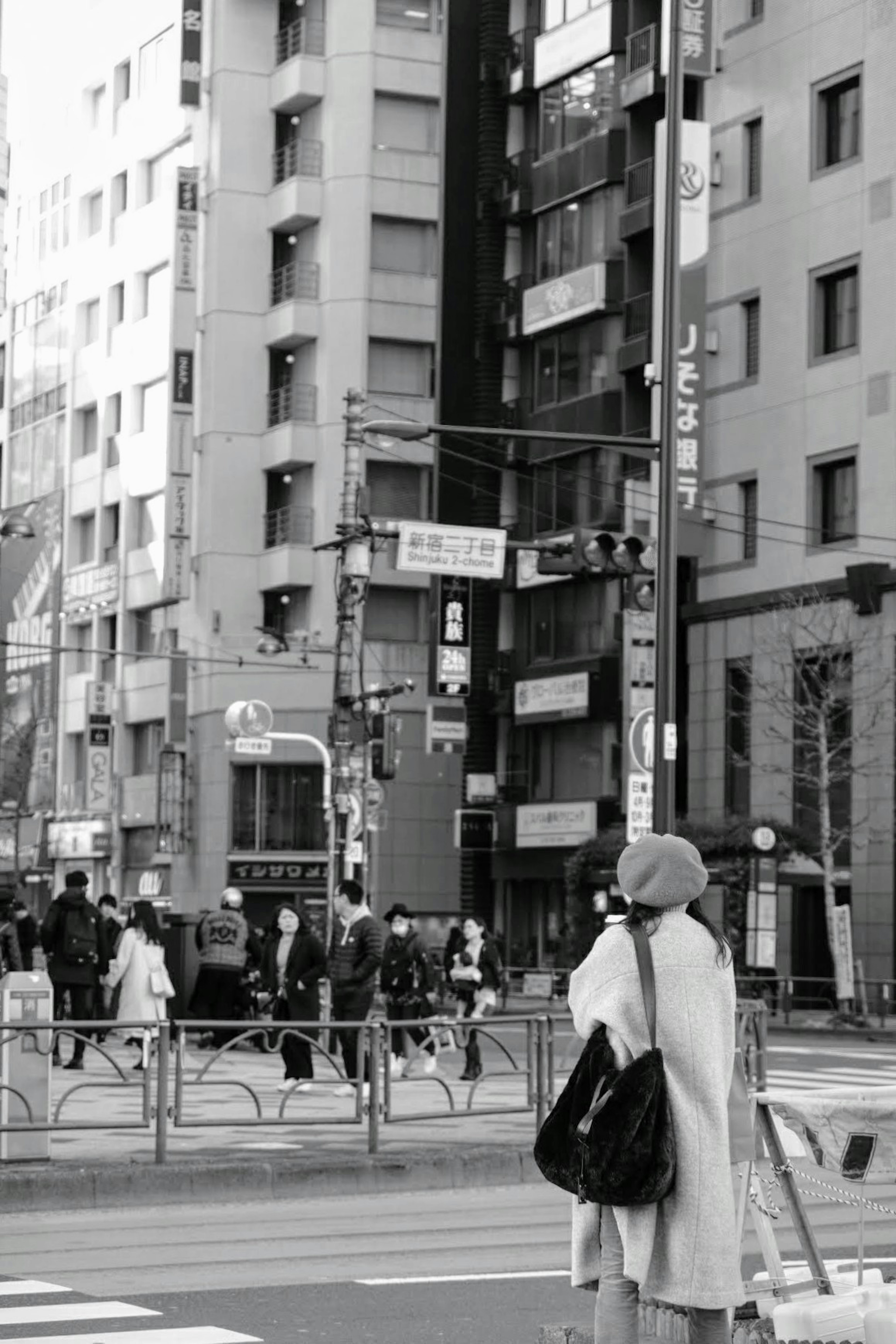 都市の通りで立っている女性と周囲の人々の様子