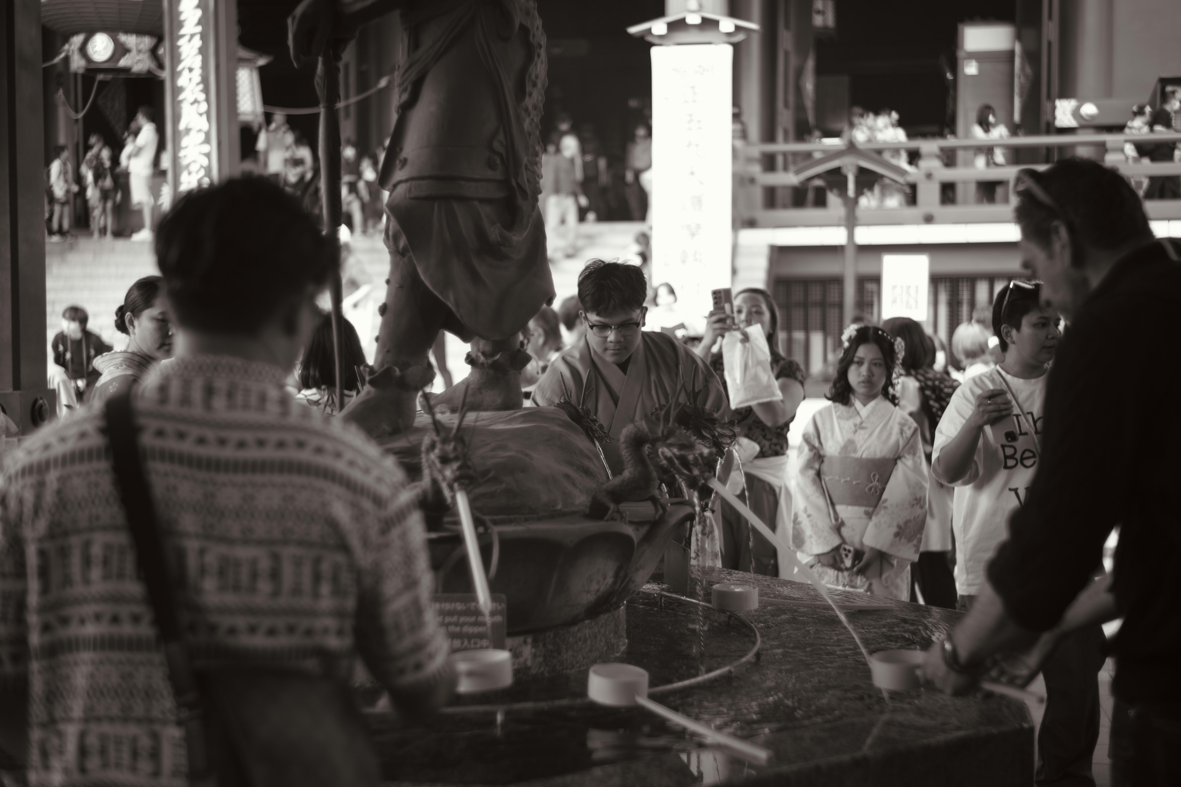 Scène d'un sanctuaire avec des personnes tirant de l'eau en tenue traditionnelle photo en noir et blanc