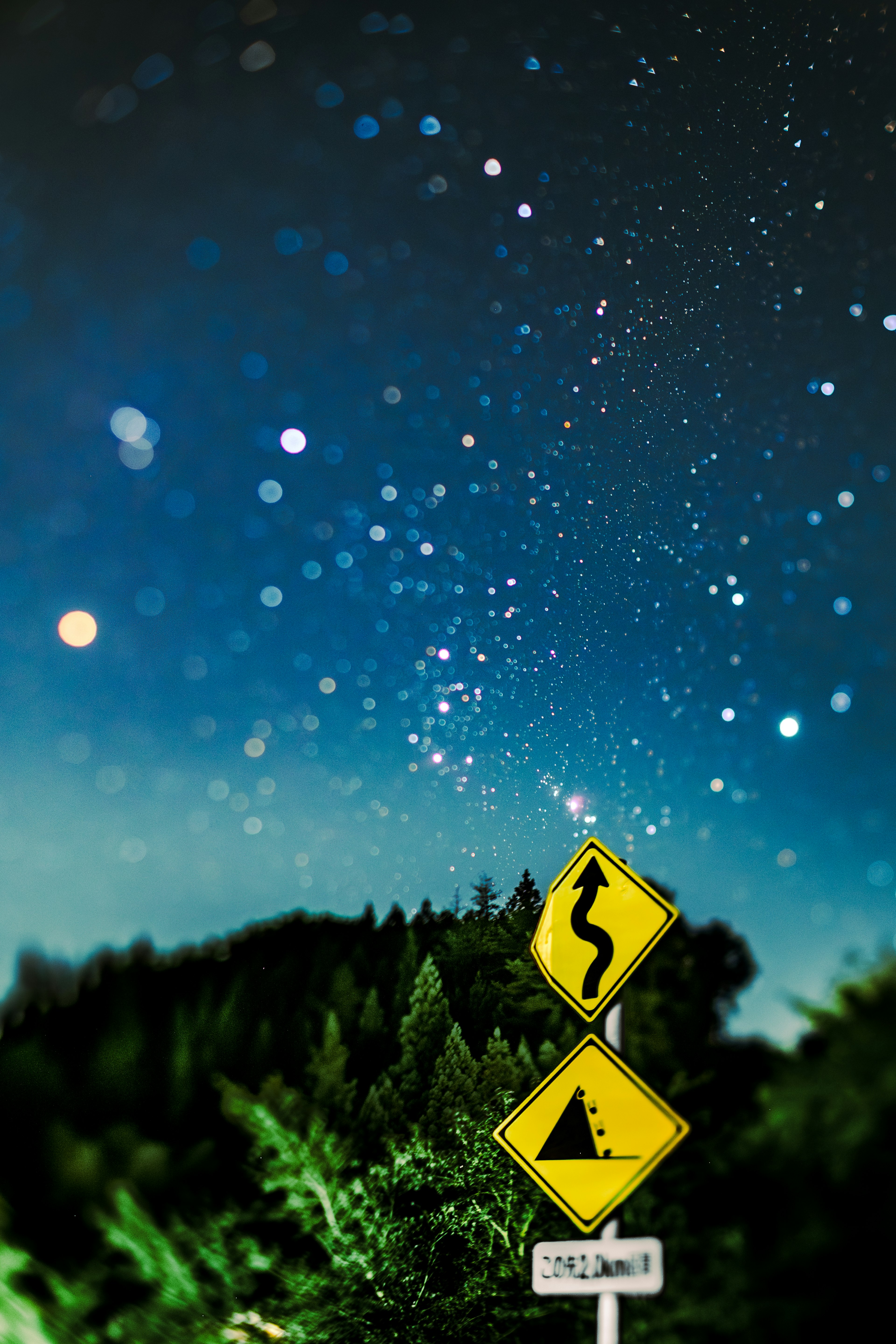 夜空に星々が輝く中に曲がりくねった道路標識と危険標識が立っている風景