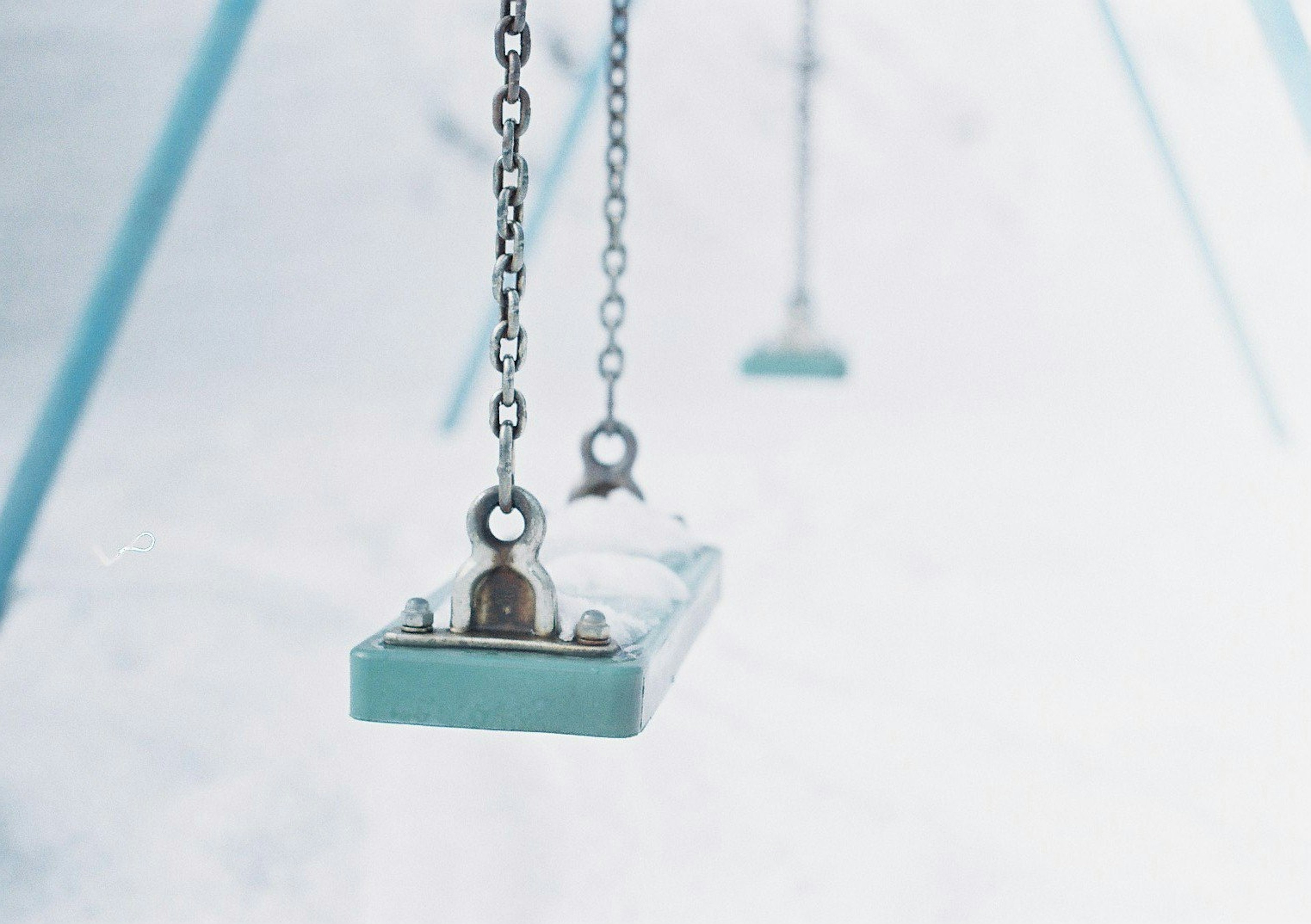 Acercamiento de un columpio azul con cadenas de metal en un entorno de parque infantil minimalista