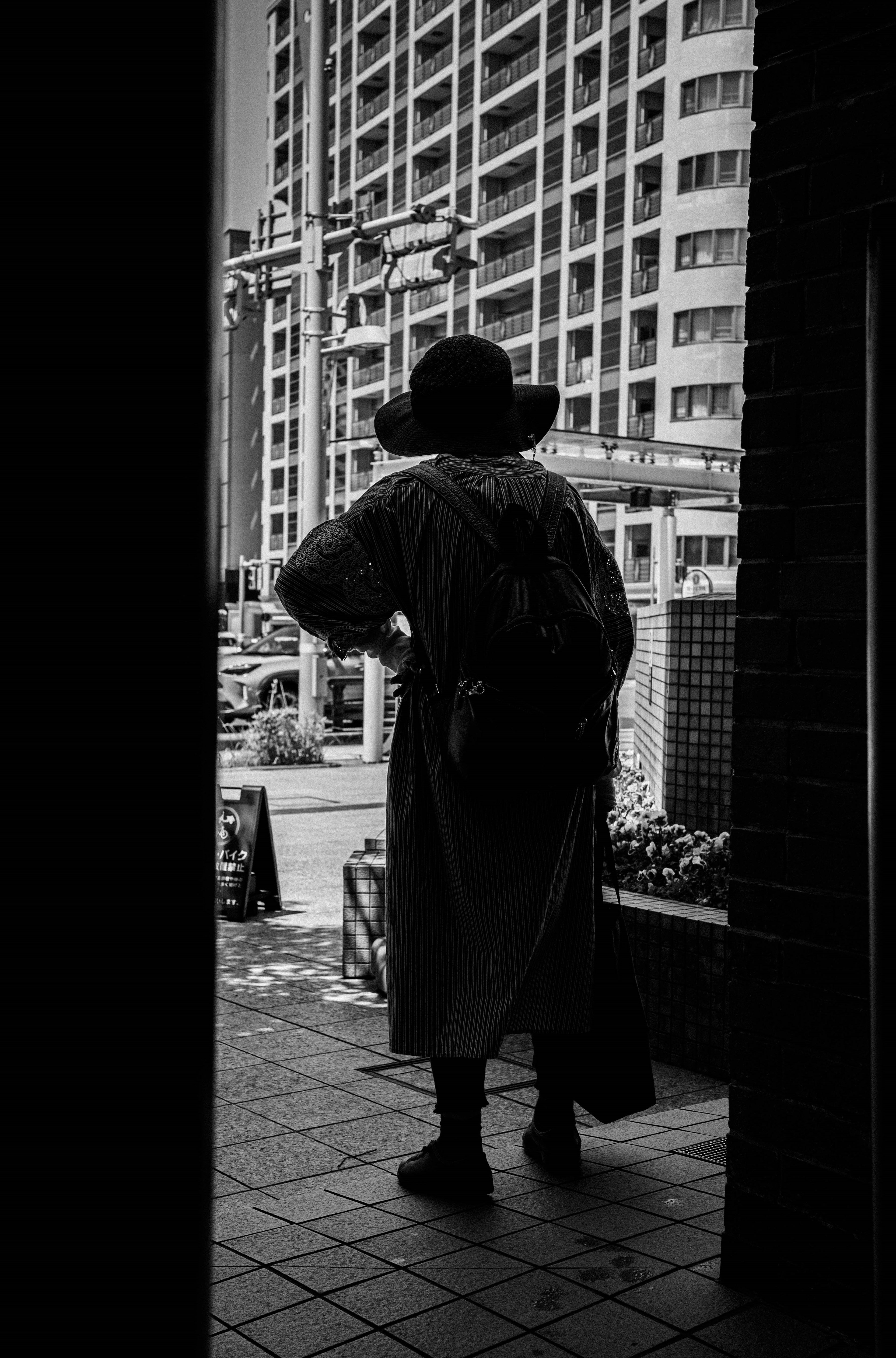 Silhouette of a person standing in front of a building in black and white