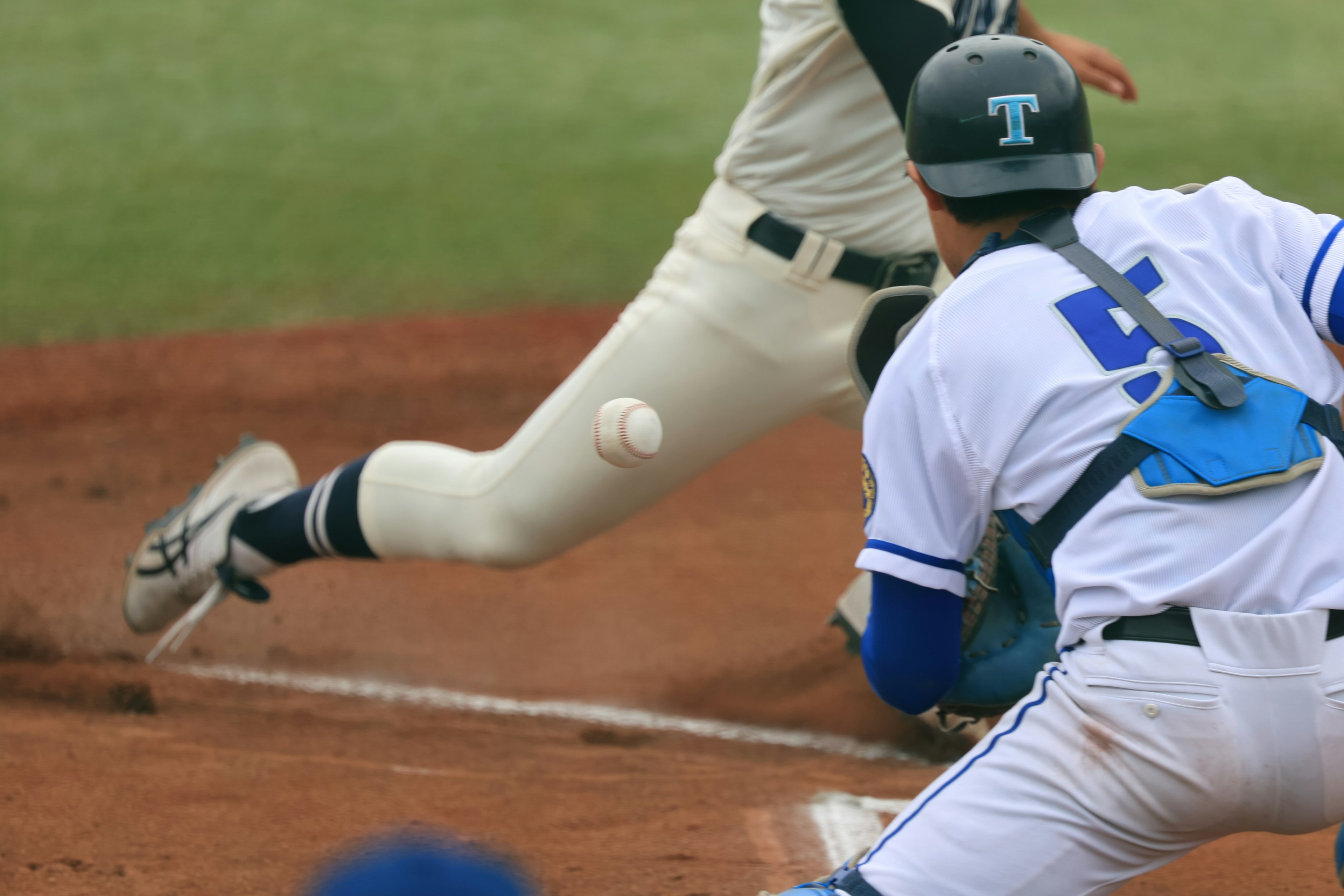 A moment in a baseball game with the catcher attempting to catch a ball