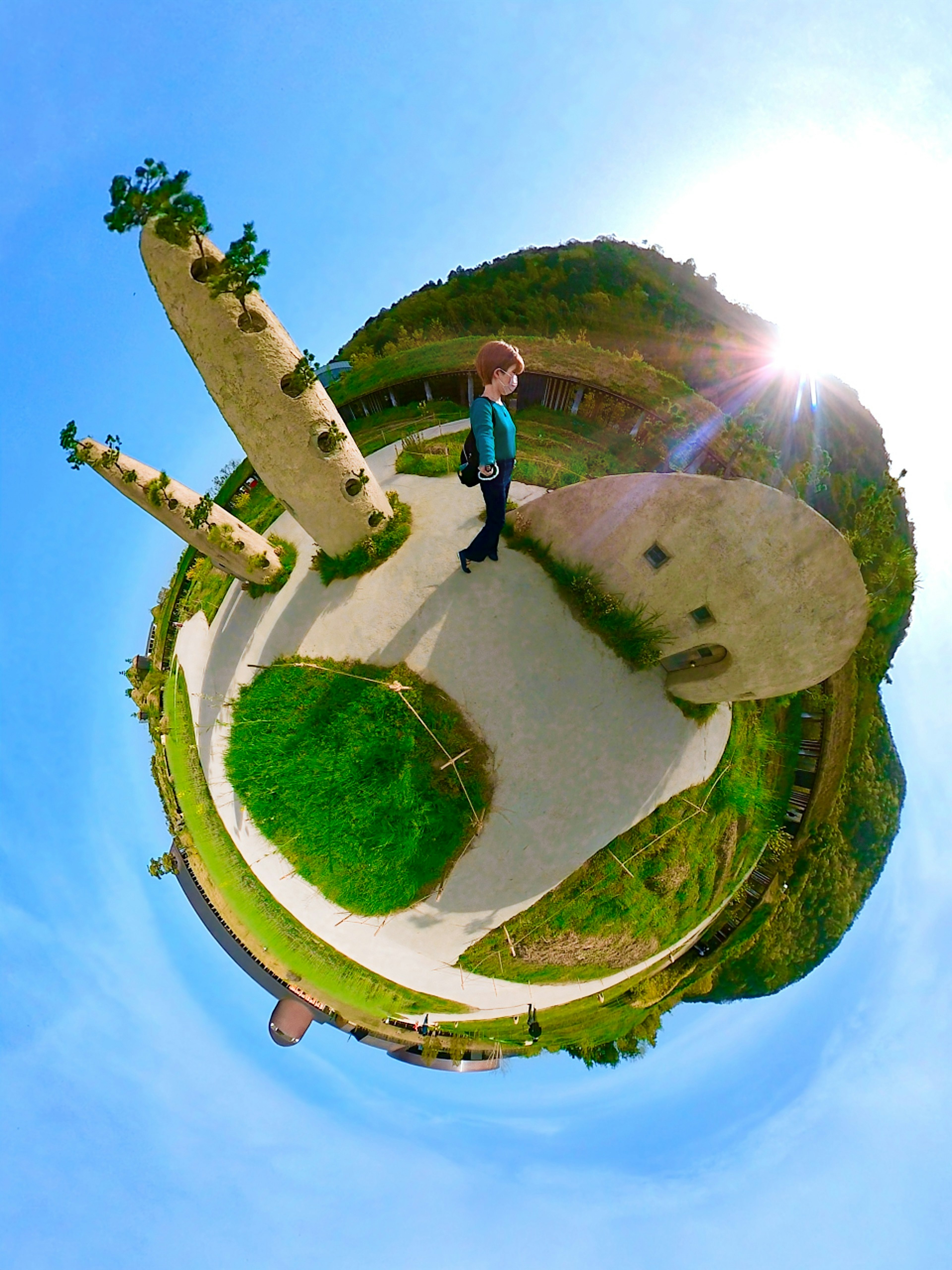 A boy standing on a small planet-like landscape with green hills