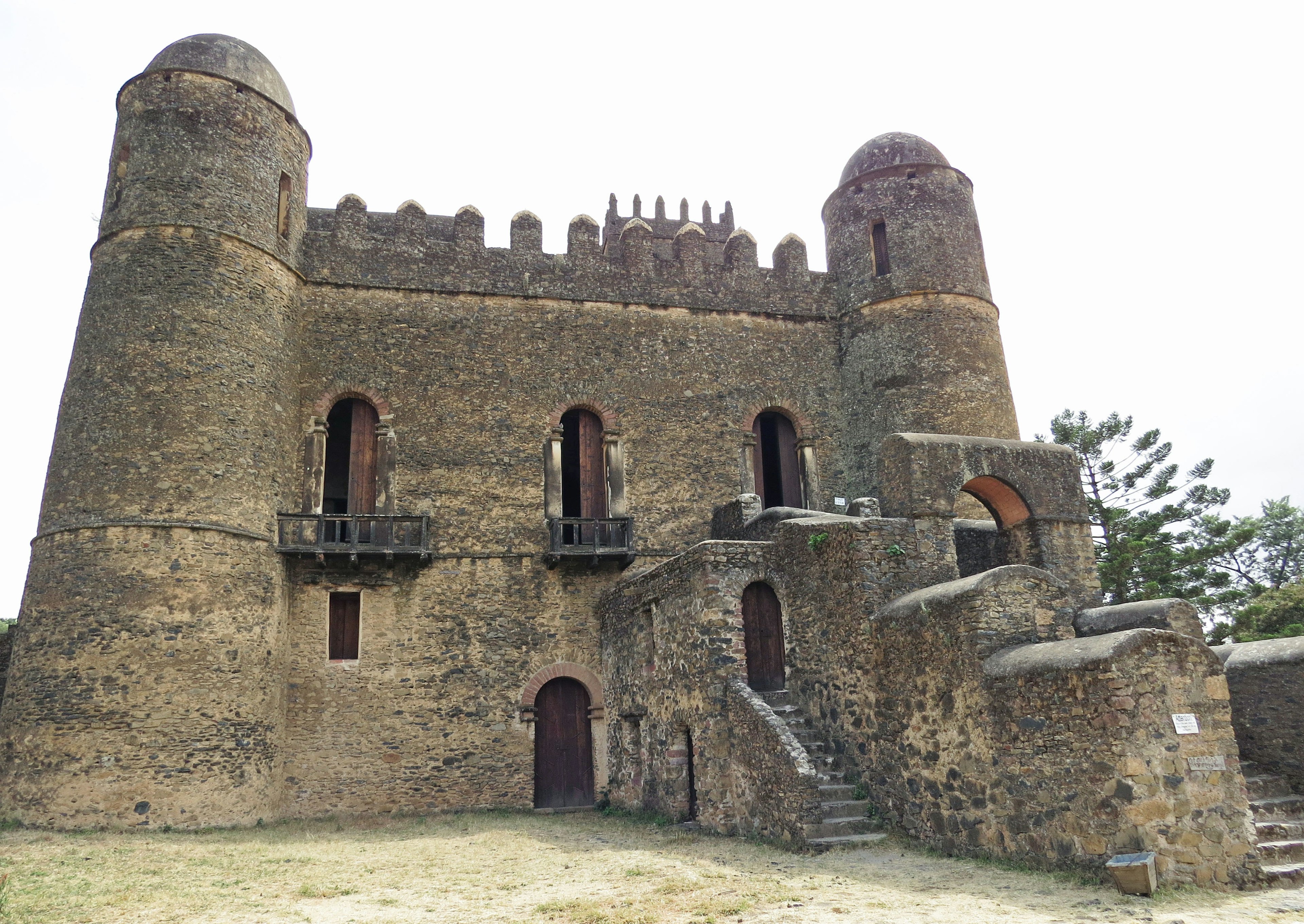 Esterno di un antico castello in pietra con torri e scale