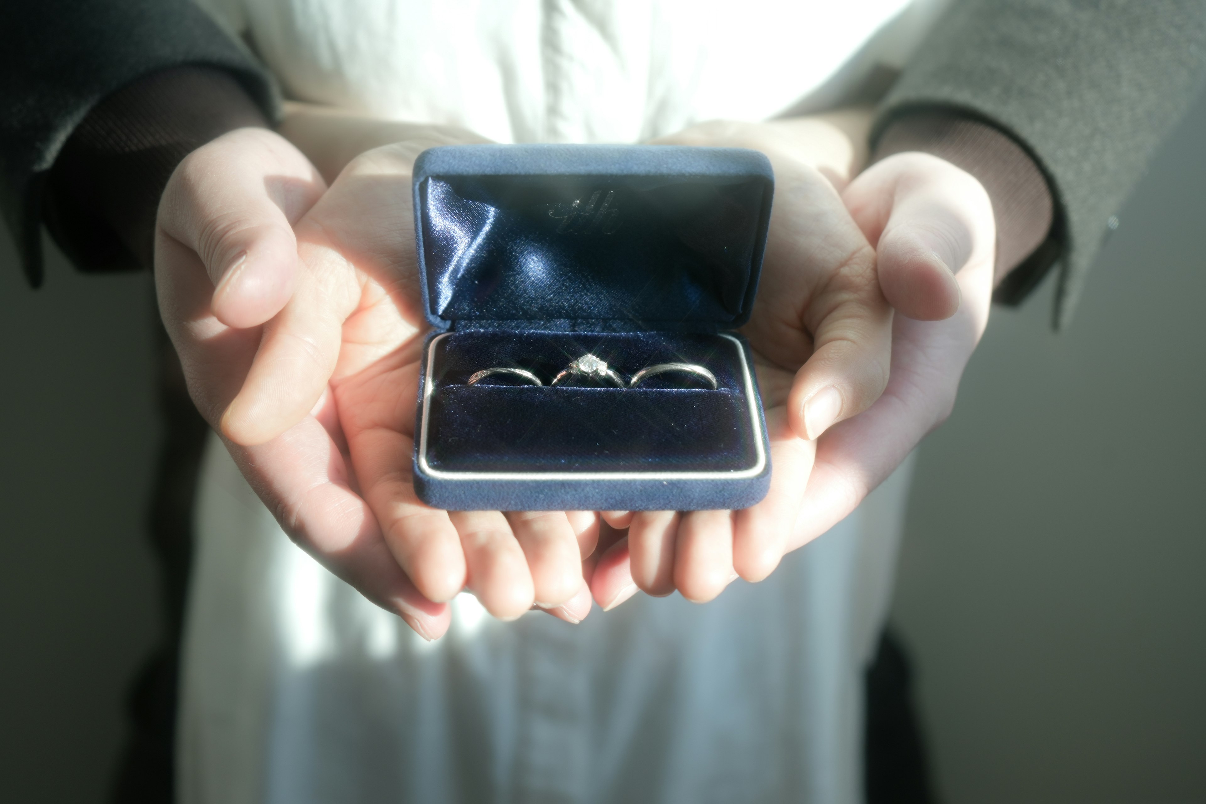 Person holding a ring box containing three rings