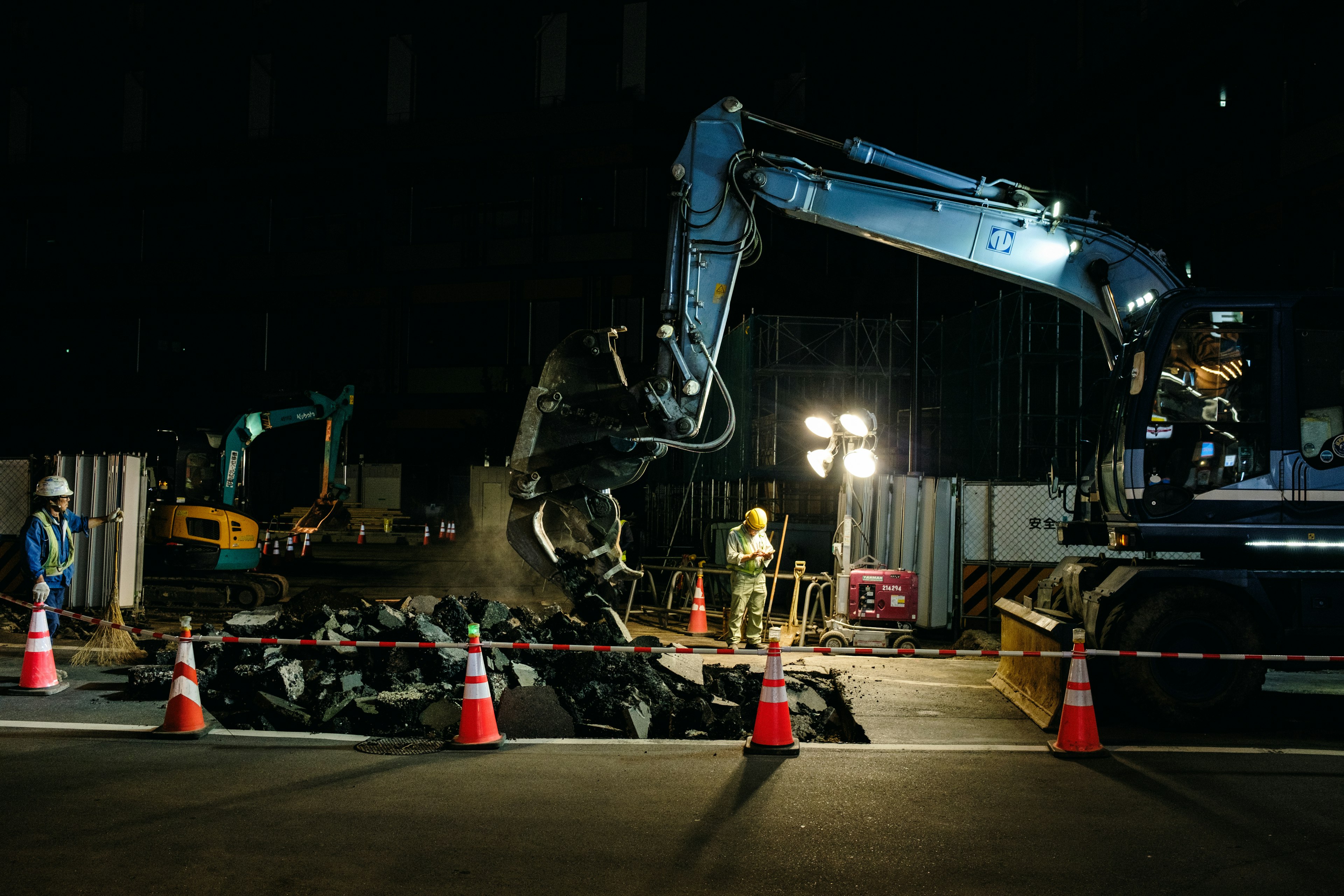 Sitio de construcción de noche con maquinaria y trabajadores