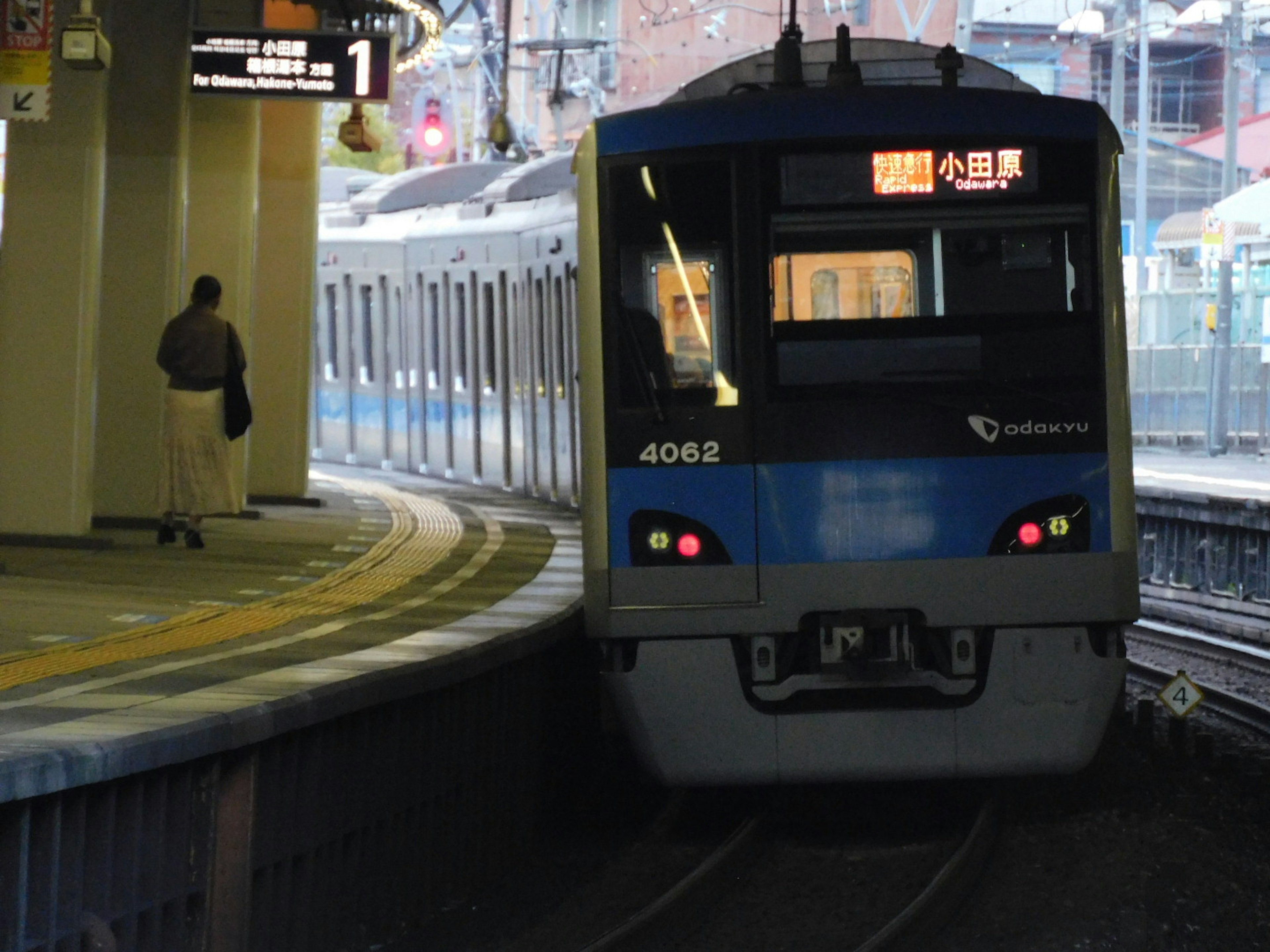 青い電車が駅に到着するシーン 乗客がホームに立っている