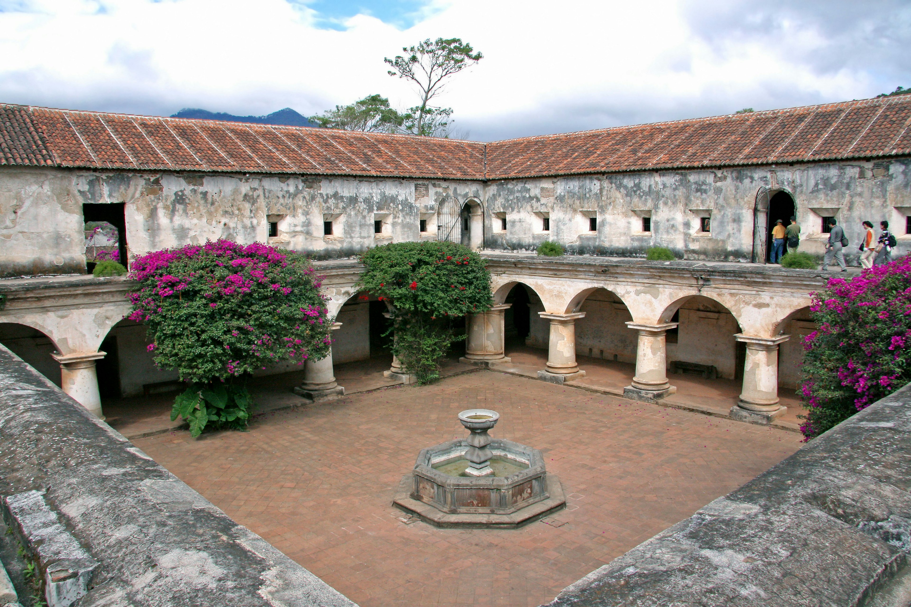 Intérieur d'un bâtiment historique avec une belle cour arborée de fleurs et d'une fontaine