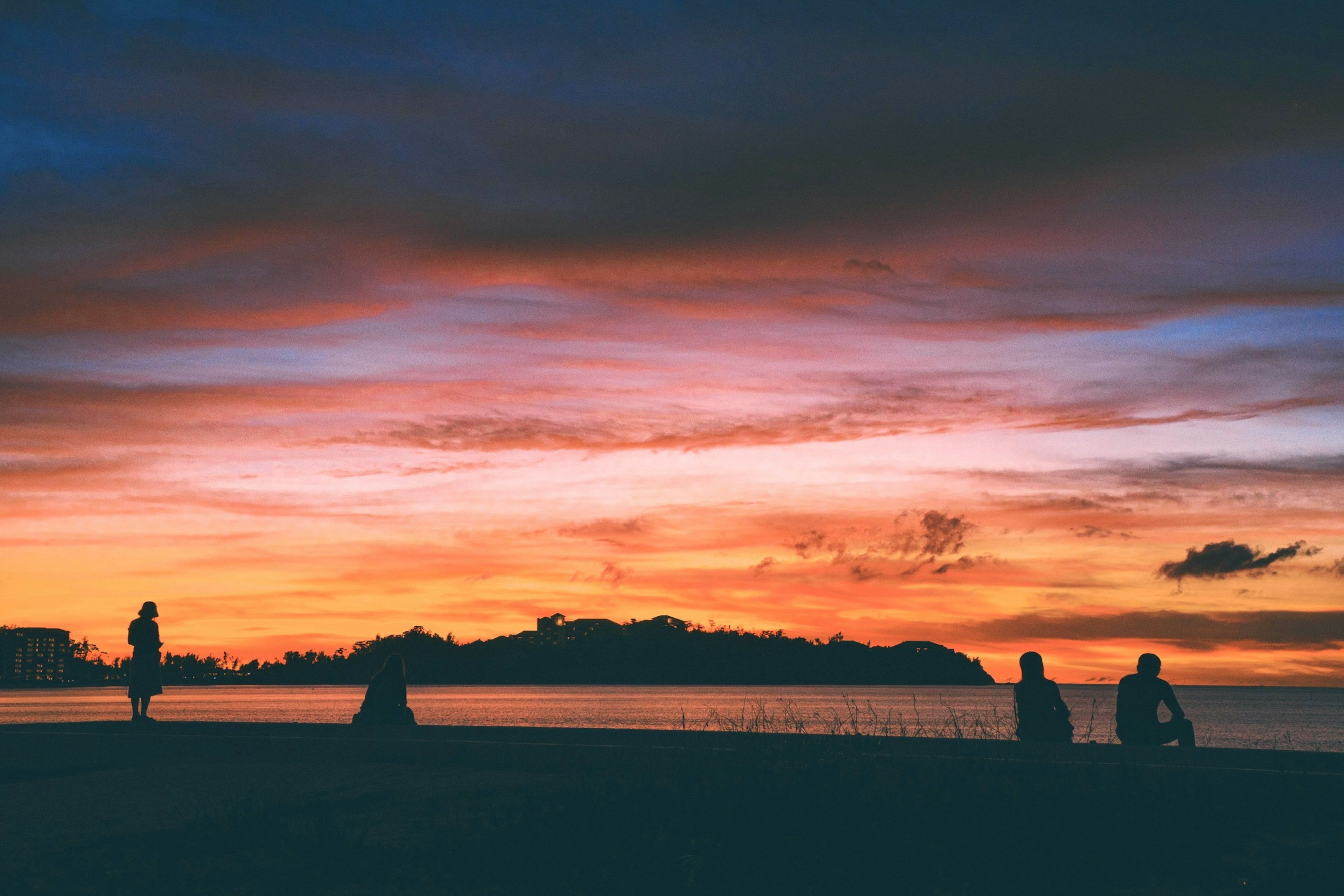 Silhouette von Menschen gegen einen bunten Sonnenuntergang über dem Meer