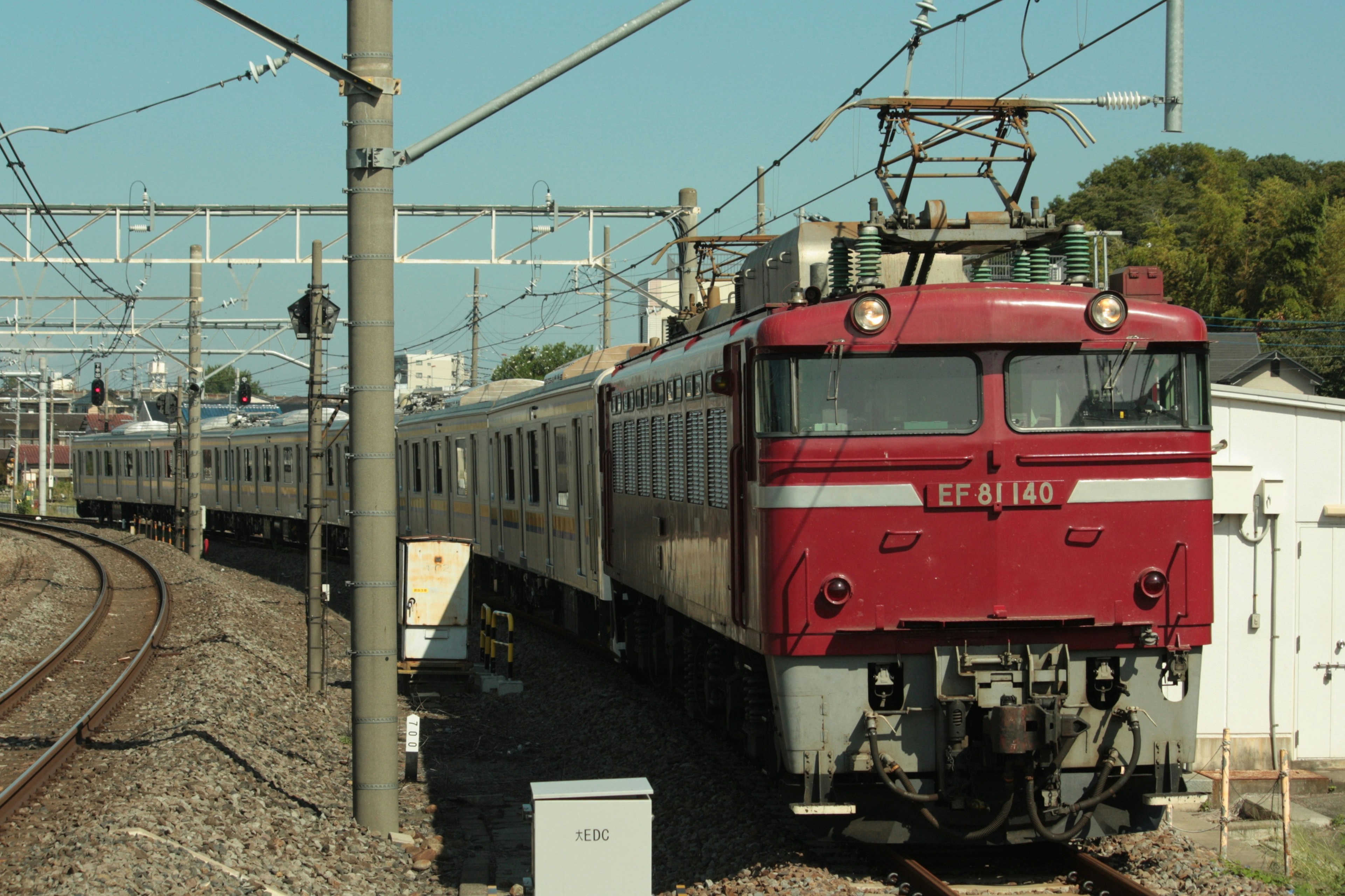 赤い電気機関車が列車を牽引している風景