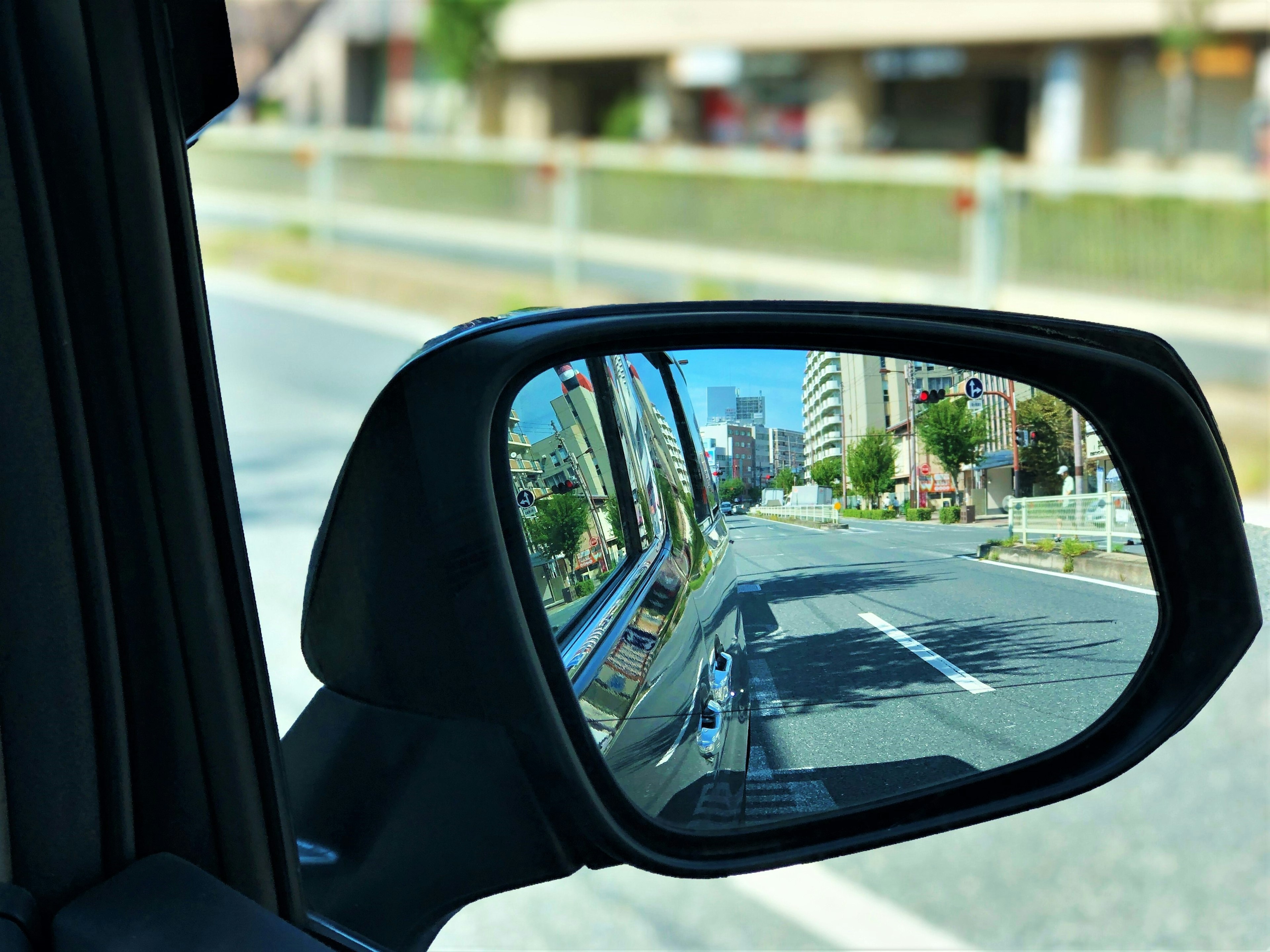 Cityscape and road reflected in a car side mirror